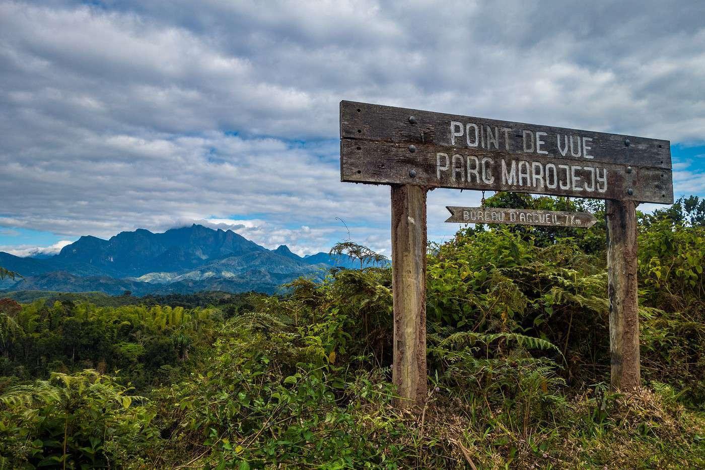 Cartello in legno che indica un punto panoramico nel parco Marojejy, con vista sulle montagne boscose del Madagascar