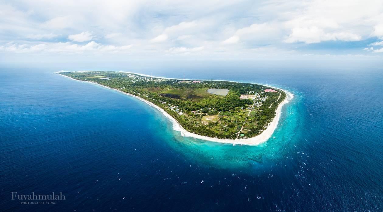 Vista aerea di un’isola tropicale circondata da barriere coralline turchesi e spiagge bianche immacolate