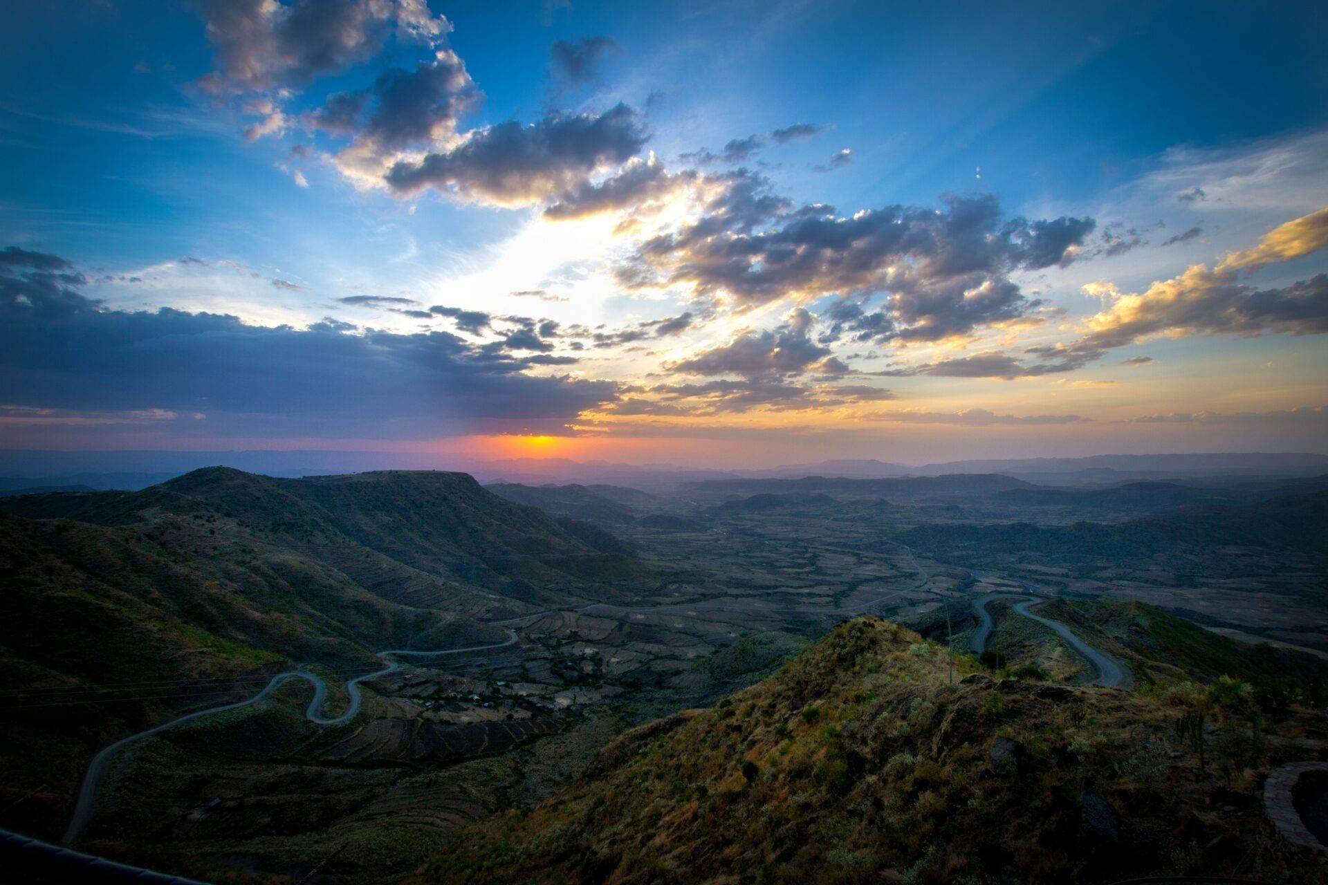 Gewundenes Flusstal, eingerahmt von grünen Hügeln bei Sonnenuntergang, afrikanische Berglandschaft