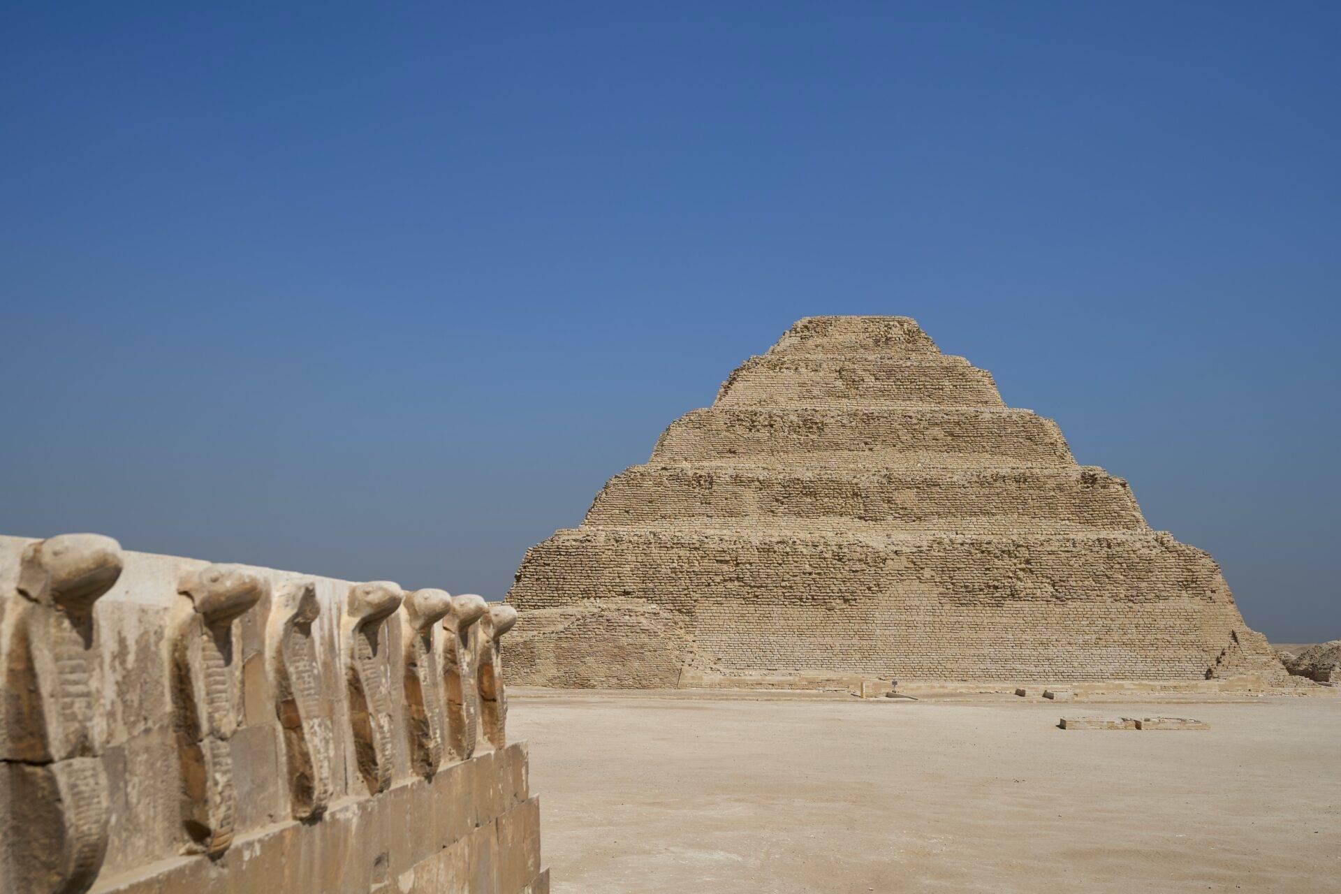 Piramide a gradini in pietra calcarea nel deserto egiziano con dettagli architettonici in primo piano