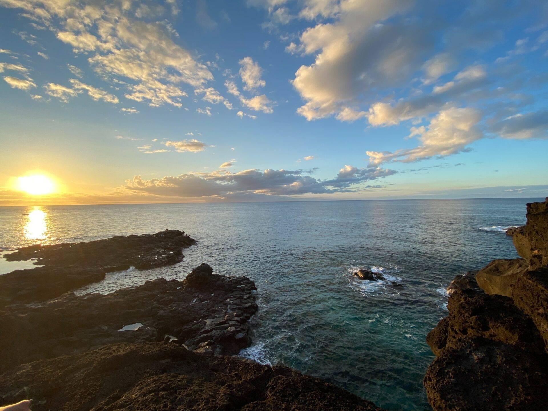 Atardecer sobre una costa rocosa del océano Índico con cielo dorado nublado y aguas turquesas