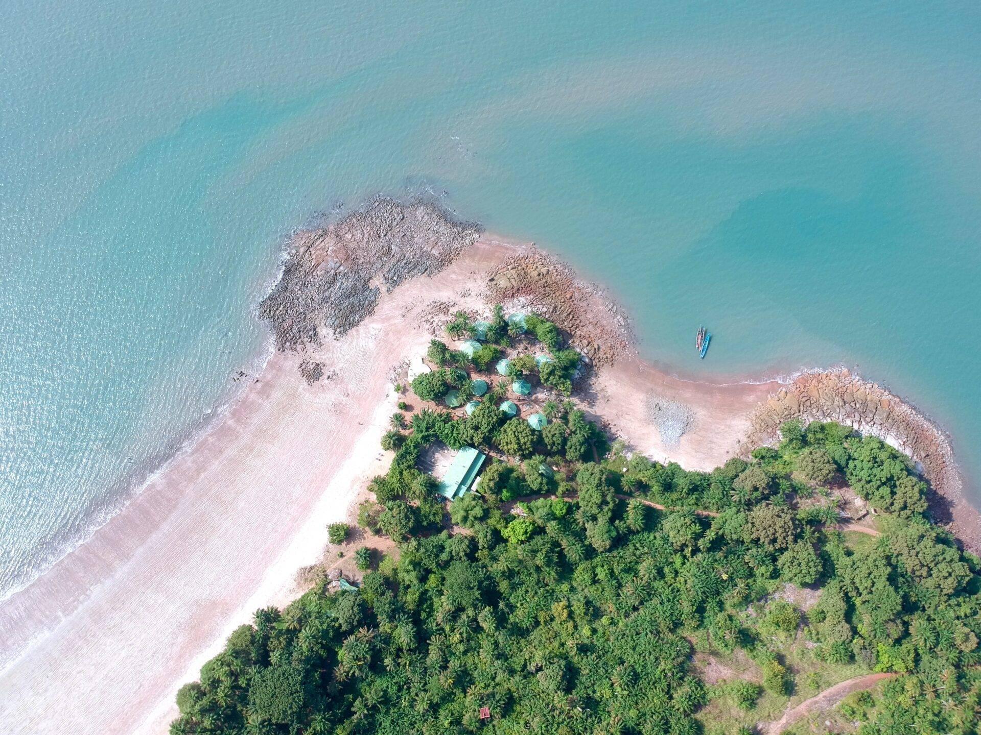 Vista aerea di un’isola costiera con spiaggia di sabbia bianca, foresta fitta e acque turchesi cristalline