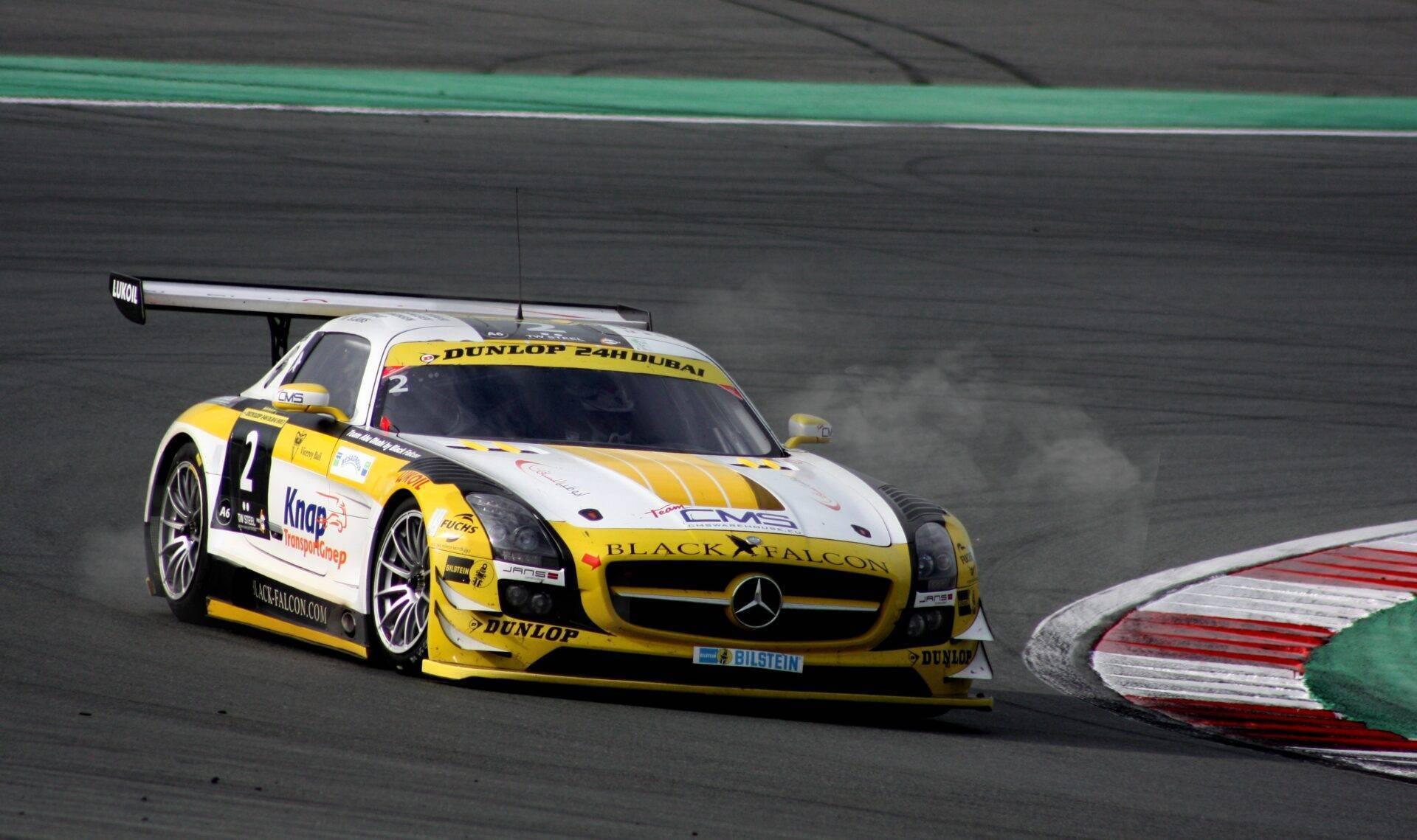 Gelb-weißer Rennwagen auf einer Motorsport-Strecke mit Kurve und Sicherheitsmarkierungen