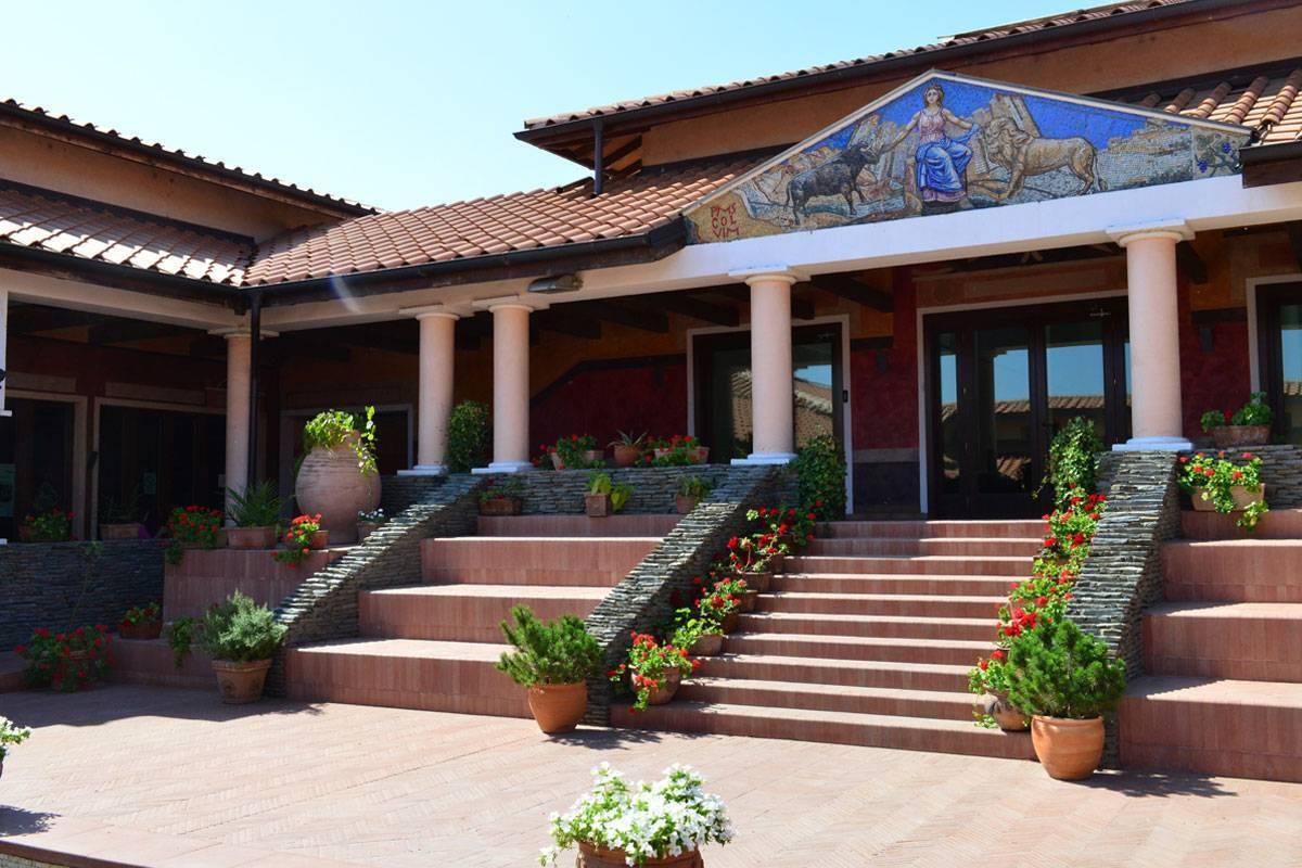 Innenhof eines orthodoxen Klosters mit weißen Säulen, religiösem Mosaik und mit Blumen geschmückten Backsteintreppen