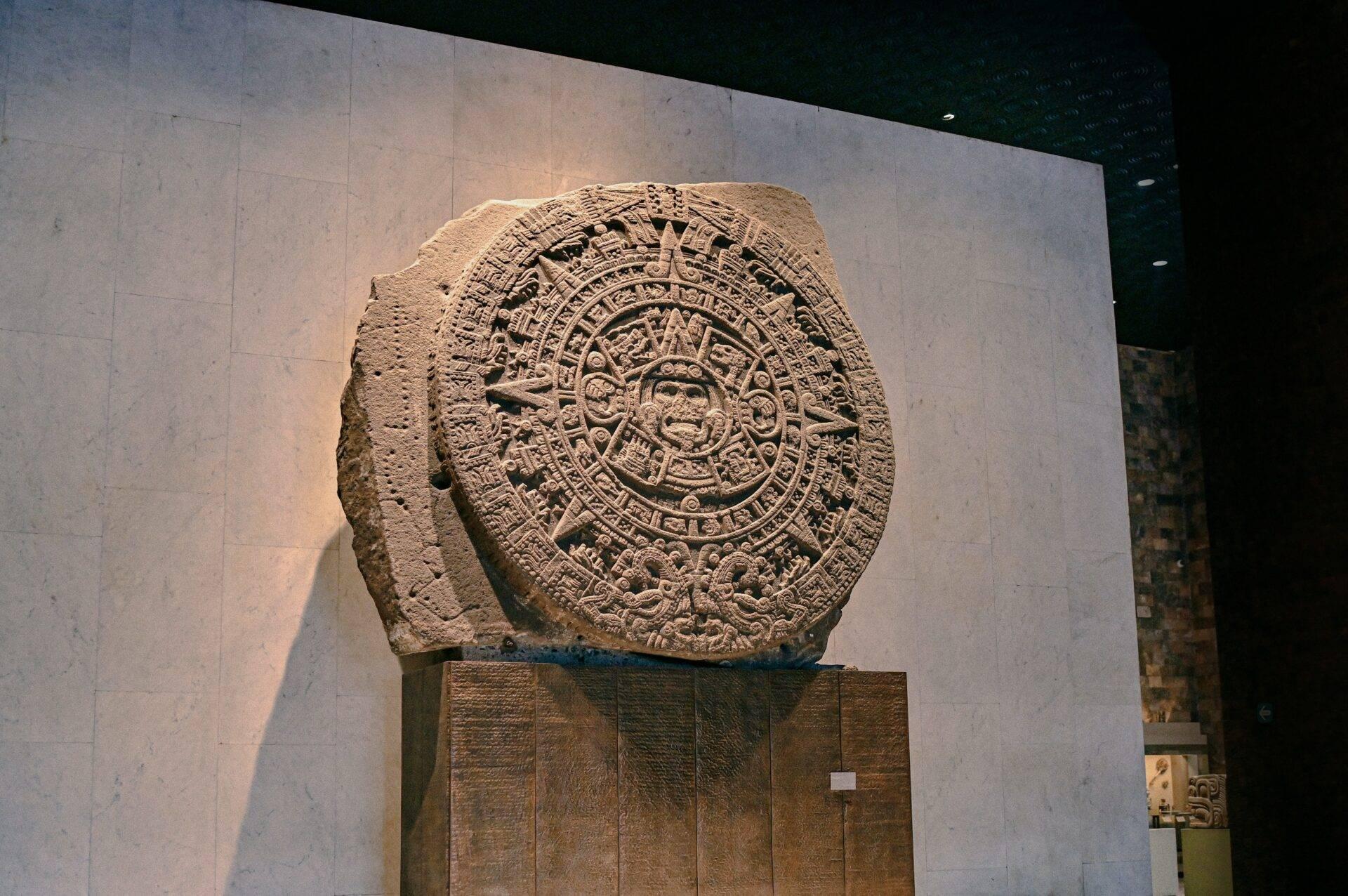 Aztekischer Kalenderstein in einem Museum mit gerichtetem Licht, das die eingravierten Details hervorhebt
