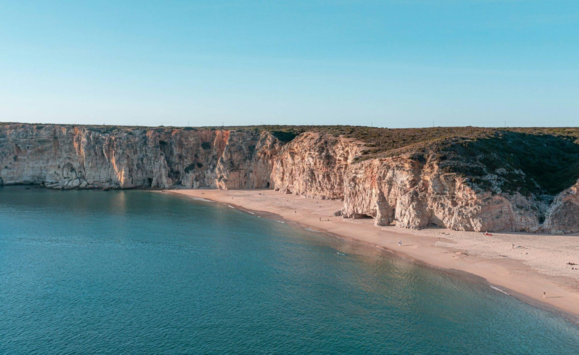 Ein feiner Sandstrand eingerahmt von imposanten weißen Kalksteinklippen über einem kristallklaren türkisfarbenen Meer