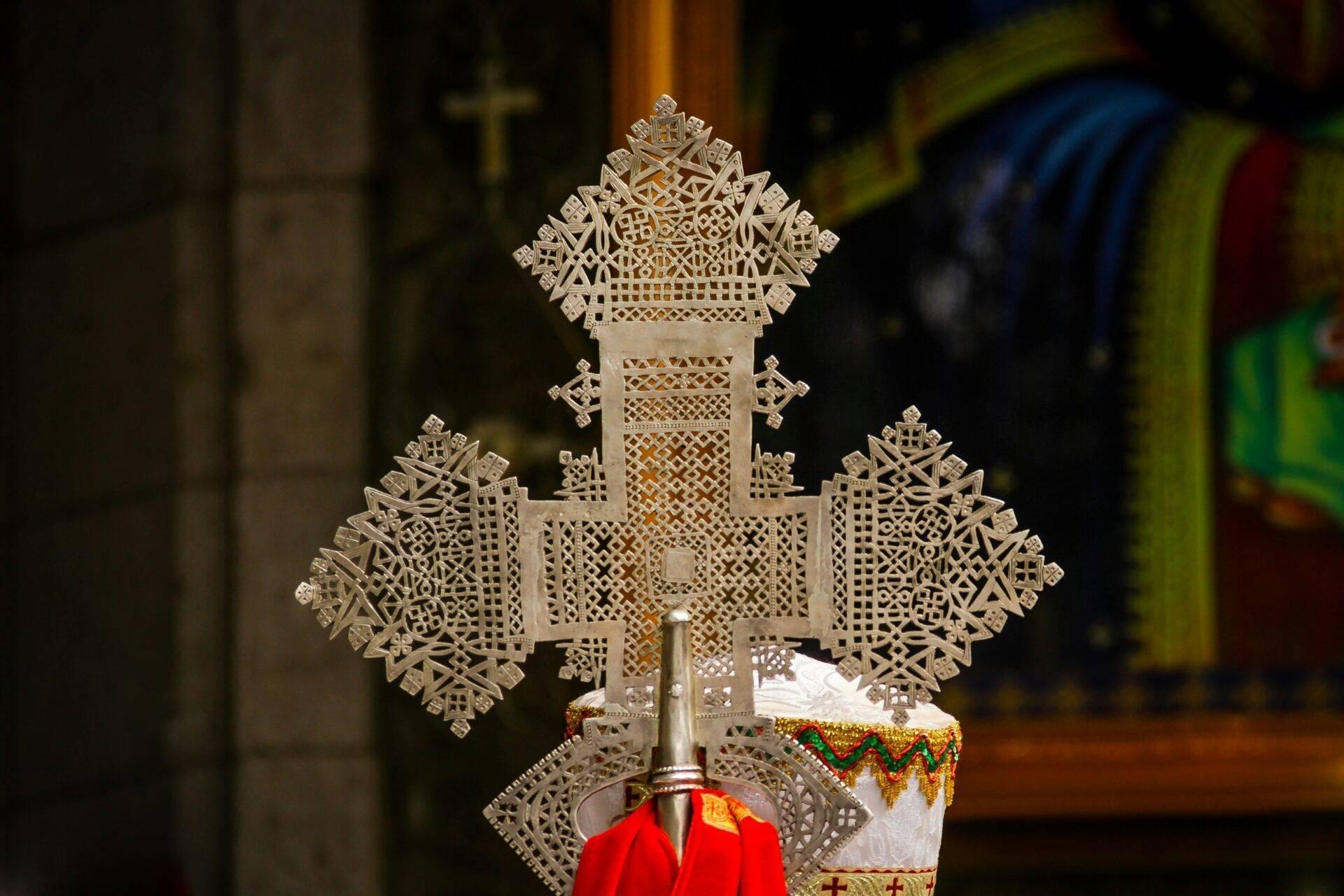 Ornate openwork metal cross inside an Ethiopian Orthodox church, with red fabric and gilded decorations