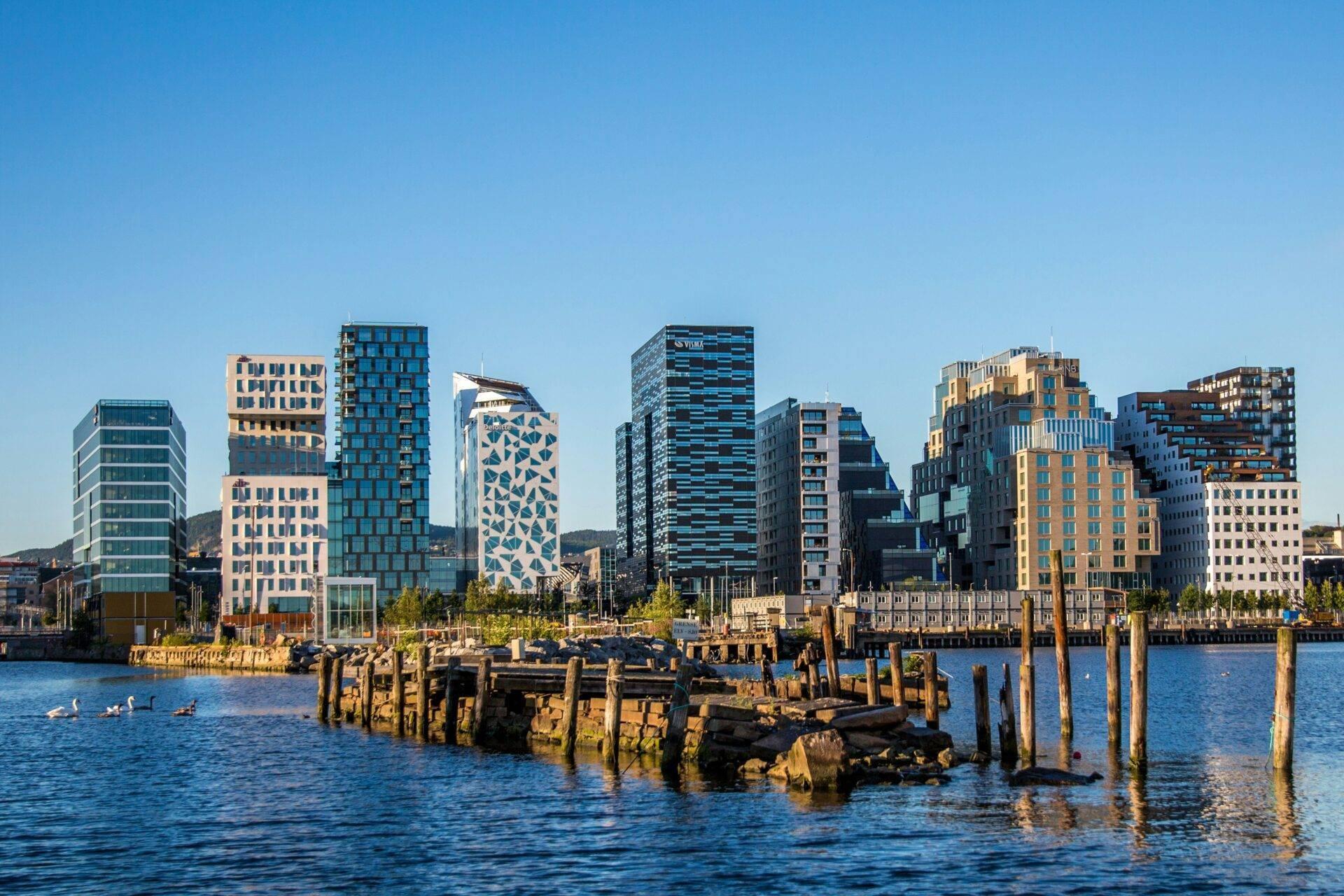 Moderne Stadtsilhouette mit bunten Gebäuden über einem Hafen mit alten Holzpfählen und blauem Wasser