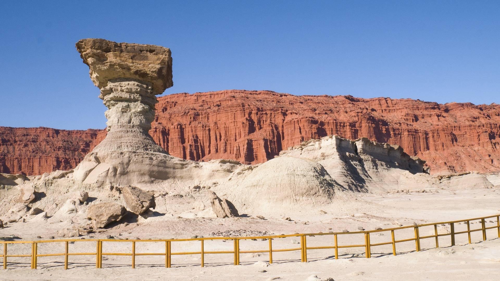 Formazione rocciosa a fungo in un paesaggio desertico arido con pareti rosse