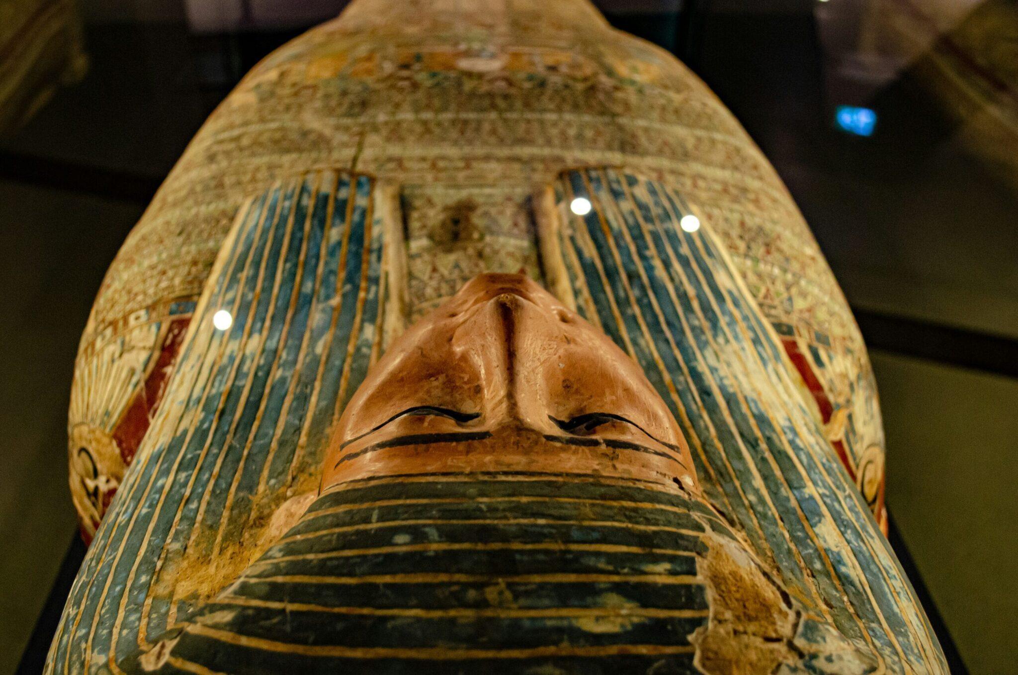 Primo piano su un sarcofago egizio mummificato con geroglifici e pitture colorate in un museo