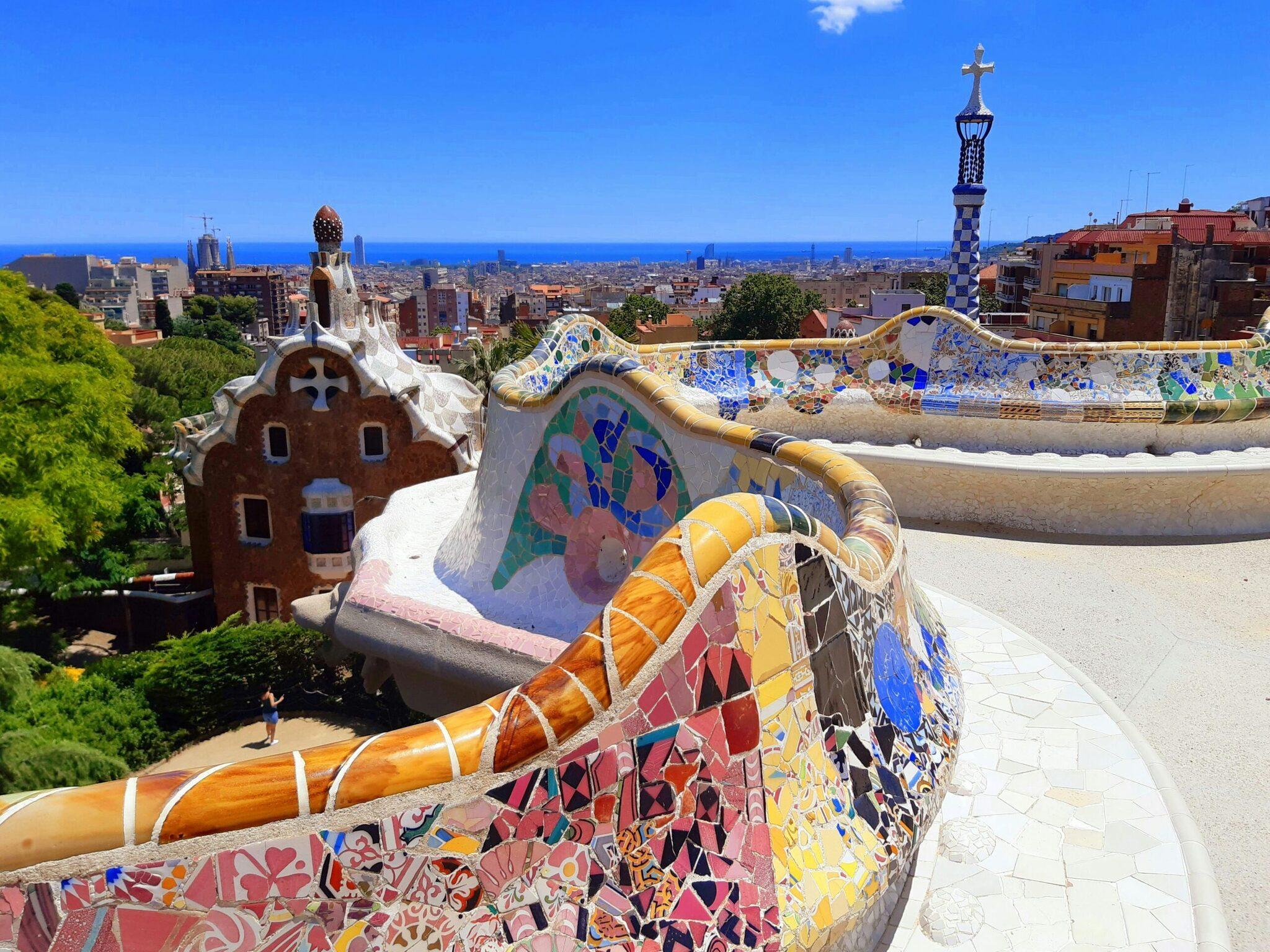 Vista aérea del parque con mosaicos de colores, arquitectura fantástica y el mar azul al fondo