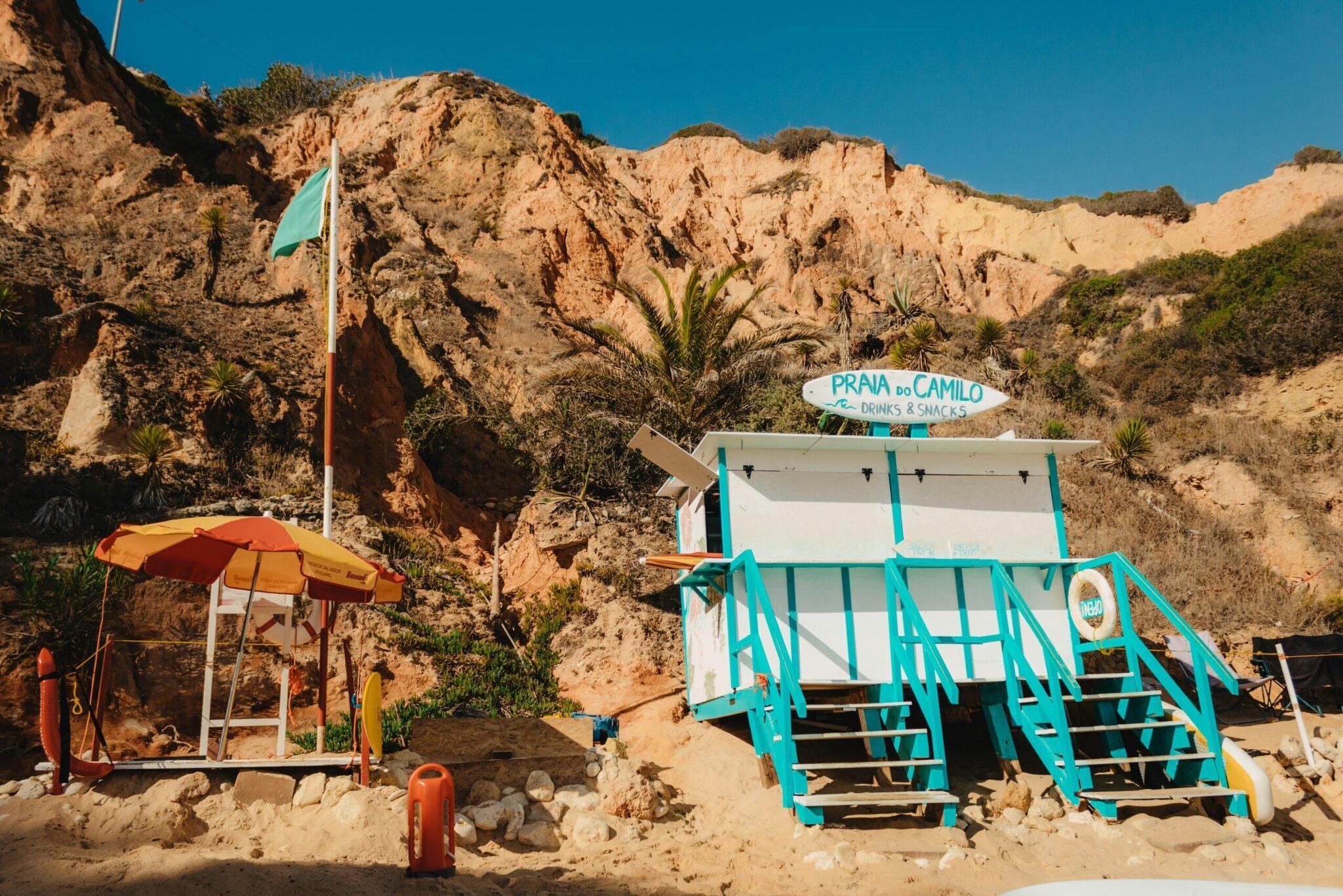 A small colourful snack bar with a sunny terrace nestled at the foot of ochre cliffs in a deserted coastal cove