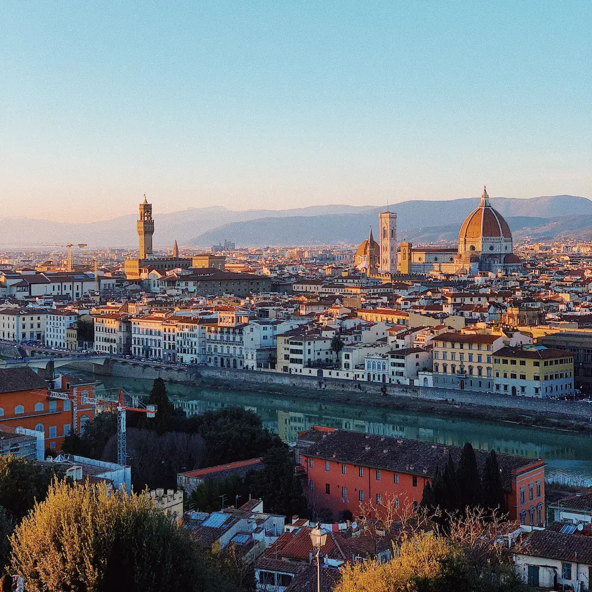 Vista panorámica de una ciudad histórica al atardecer con catedral de cúpula dorada y río que atraviesa el conjunto urbano