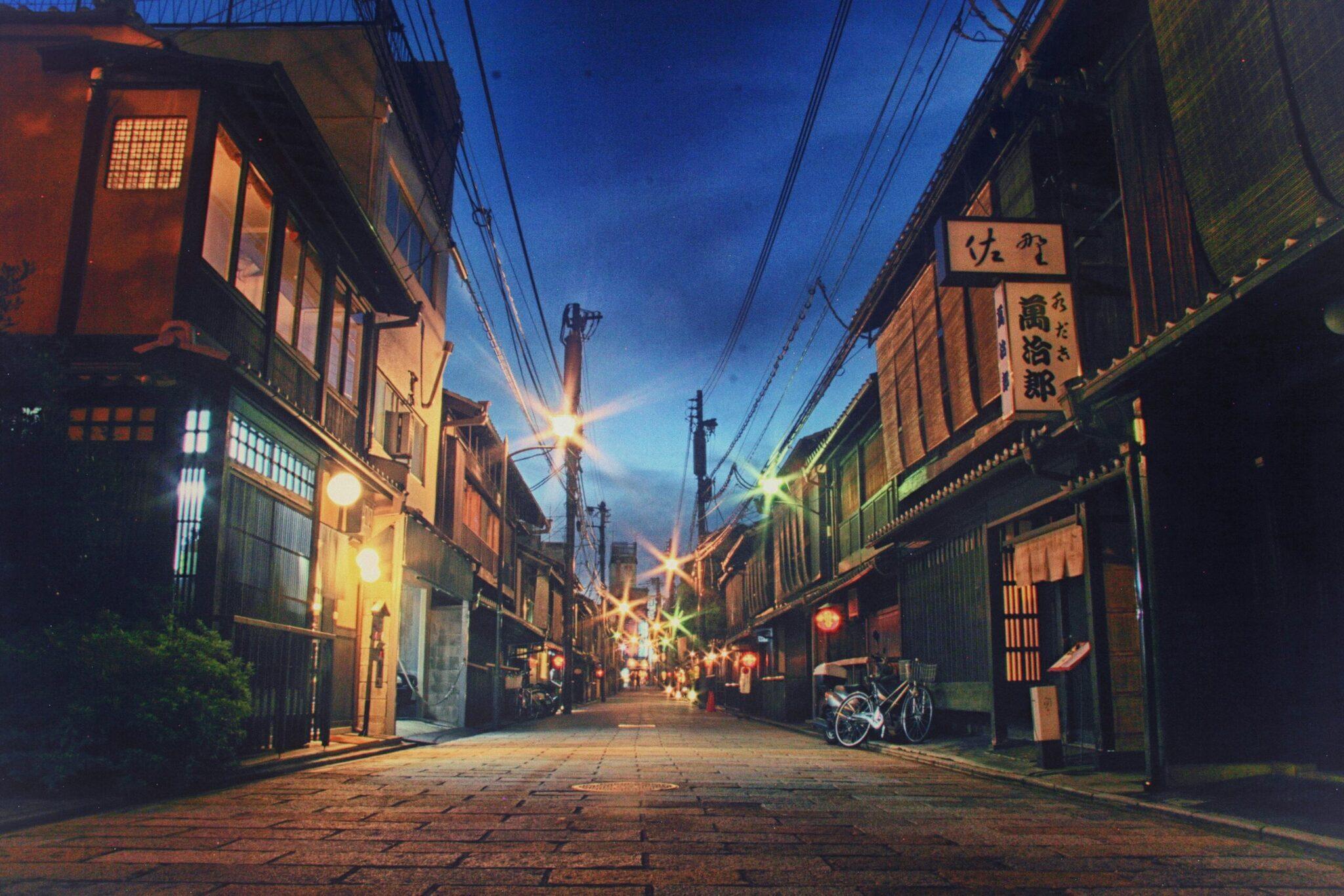 Una callejuela histórica japonesa iluminada por la noche con casas tradicionales, faroles y carteles asiáticos