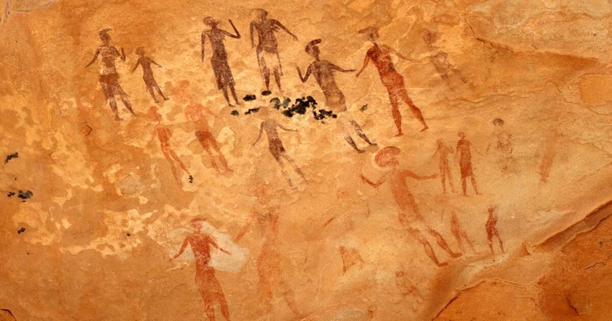 Pinturas rupestres antiguas con siluetas humanas en ocre sobre una pared rocosa desértica