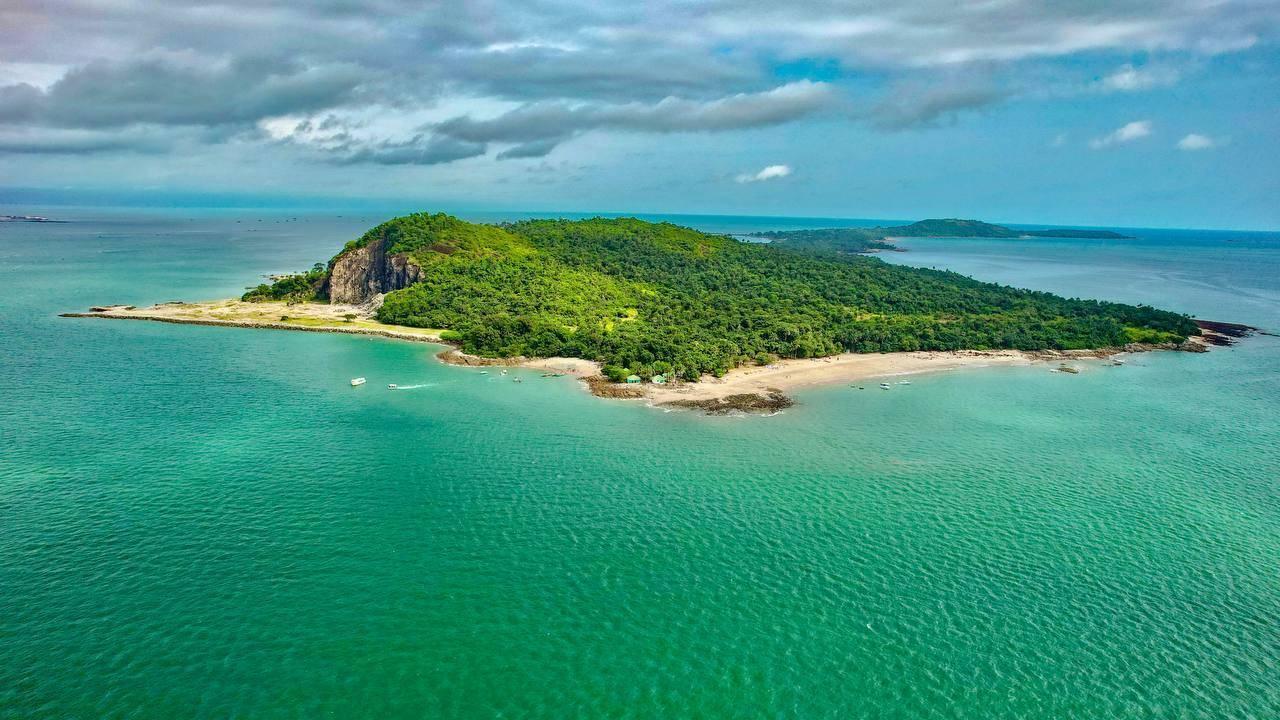 Un’isola tropicale densamente boscosa circondata da acque turchesi con spiagge di sabbia bianca e rocce costiere