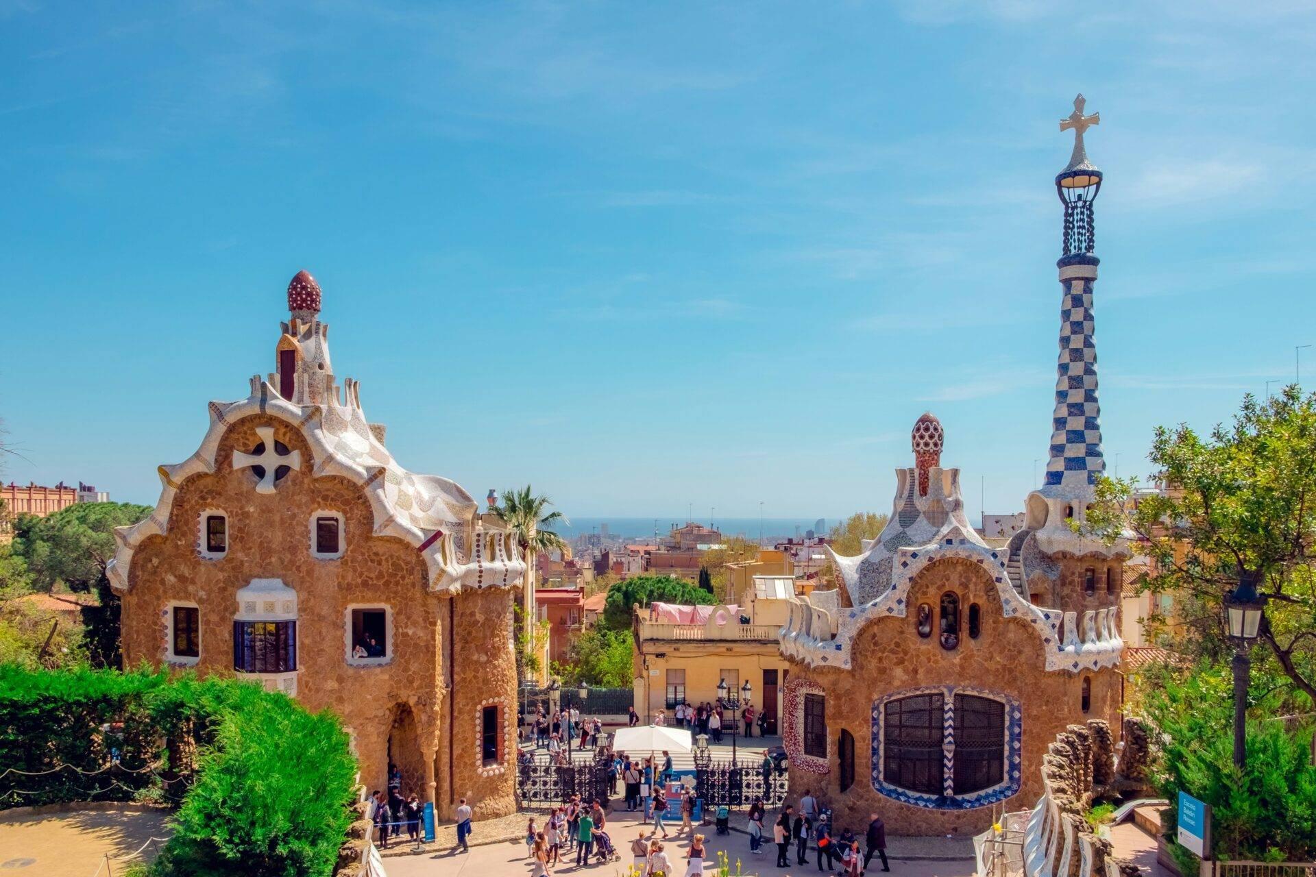 Parco con edifici architettonici colorati dalle facciate ondulate, torri ornate e vista sulla costa mediterranea
