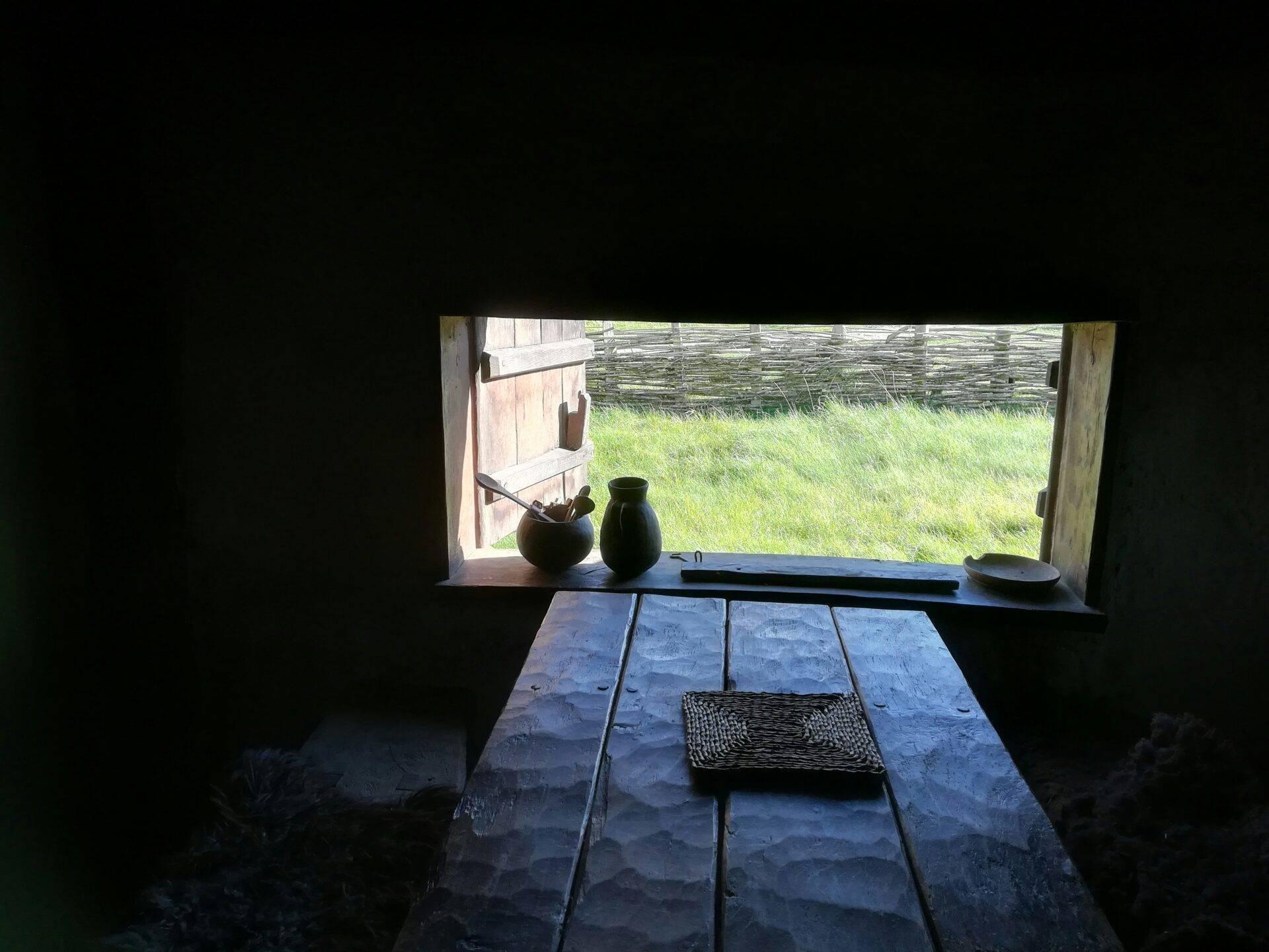 Interno di una casa tradizionale danese con tavolo in legno grezzo e vista su un prato verde