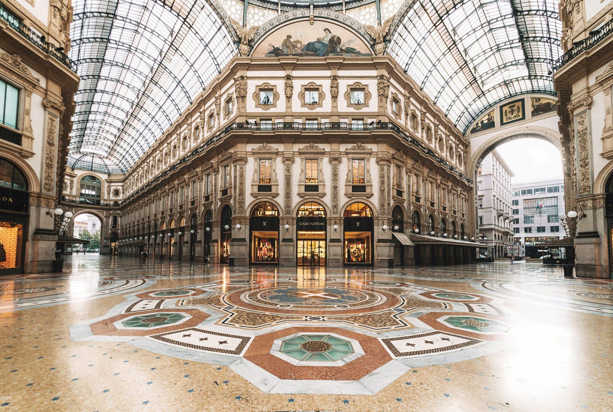 Galleria storica con volta in vetro, pavimento ornamentale e facciate neoclassiche in un’atmosfera raccolta