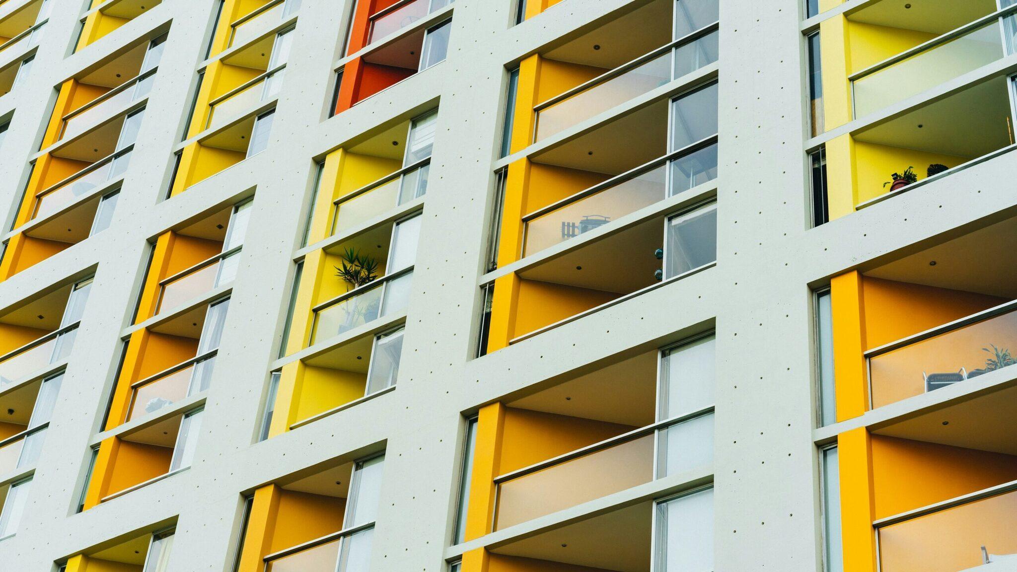 The modern facade of a residential building with yellow and white balconies, typical of contemporary urban architecture