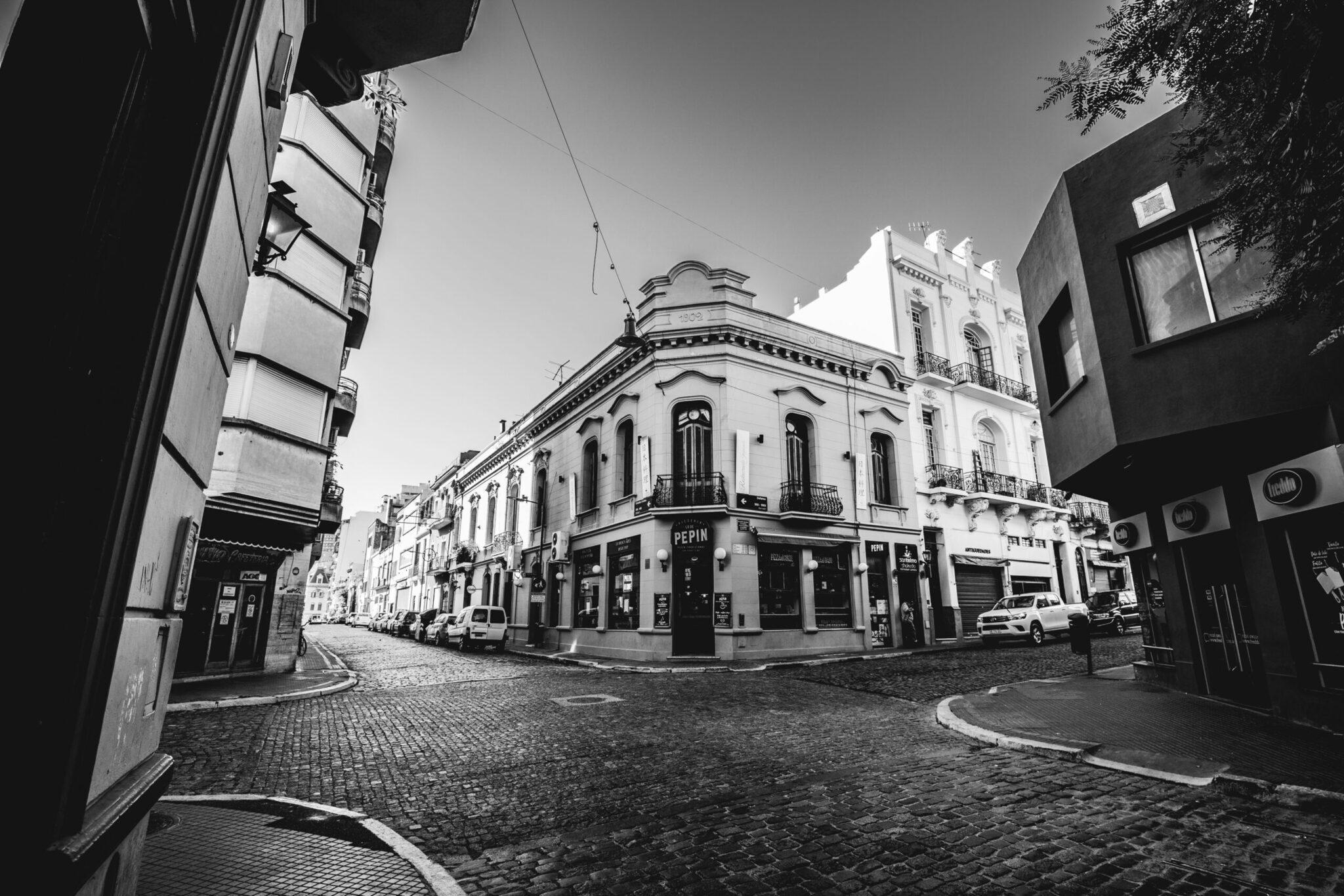 Una strada lastricata fiancheggiata da edifici coloniali bianchi con negozi al piano terra in un quartiere storico