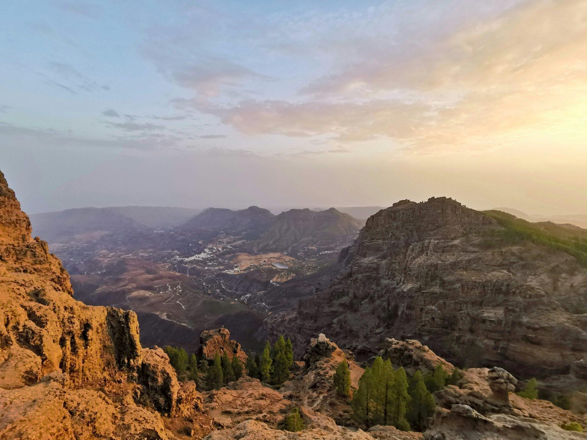 Vista panoramica di una valle di montagna con falesie rocciose al tramonto e villaggi sparsi sul territorio