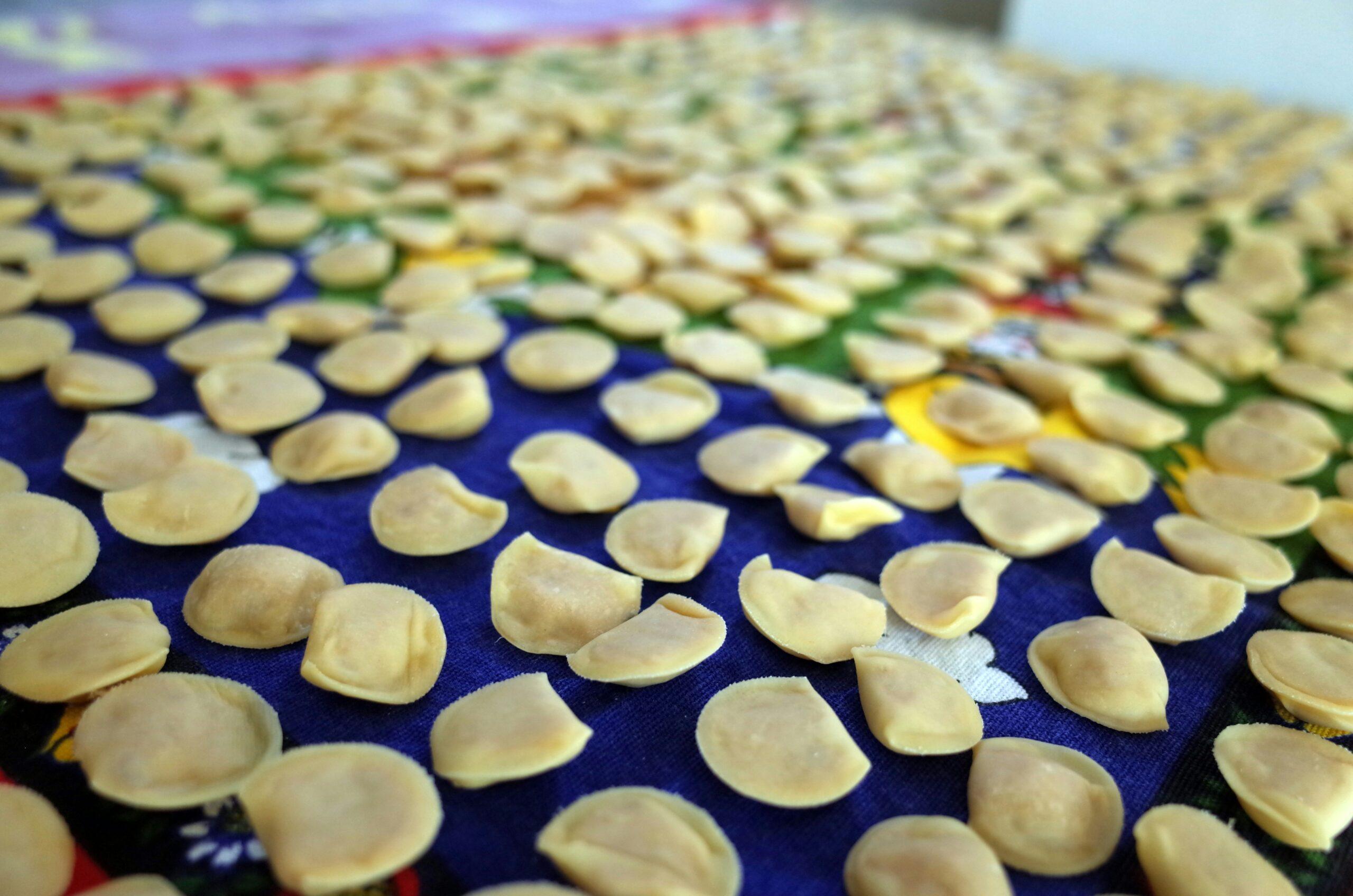 Almendras laminadas blanqueadas secándose sobre telas de colores, ilustrando la producción artesanal de especialidades regionales italianas
