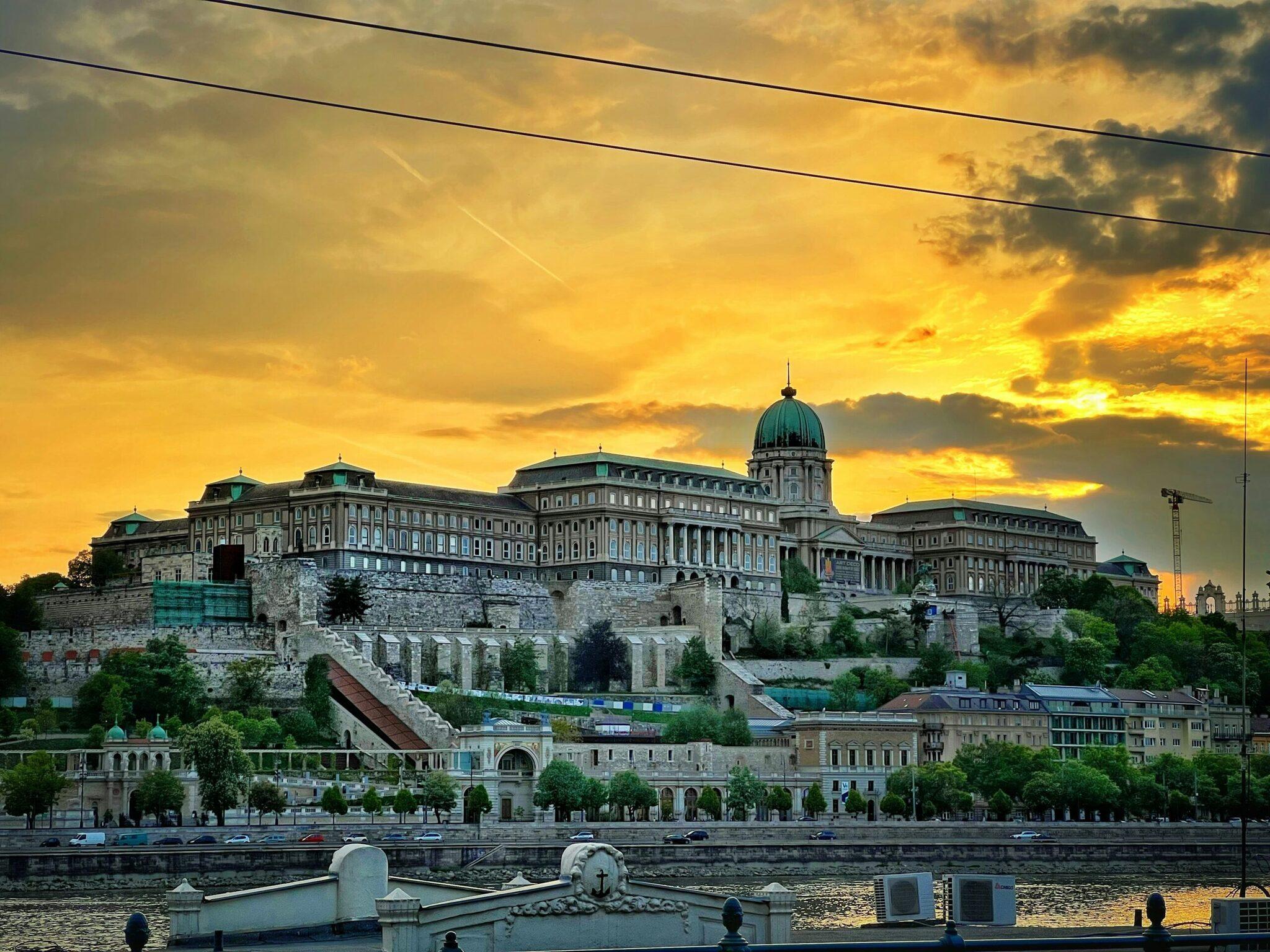 Buda Castle overlooking the Danube at golden sunset, with its historic facades and iconic central dome