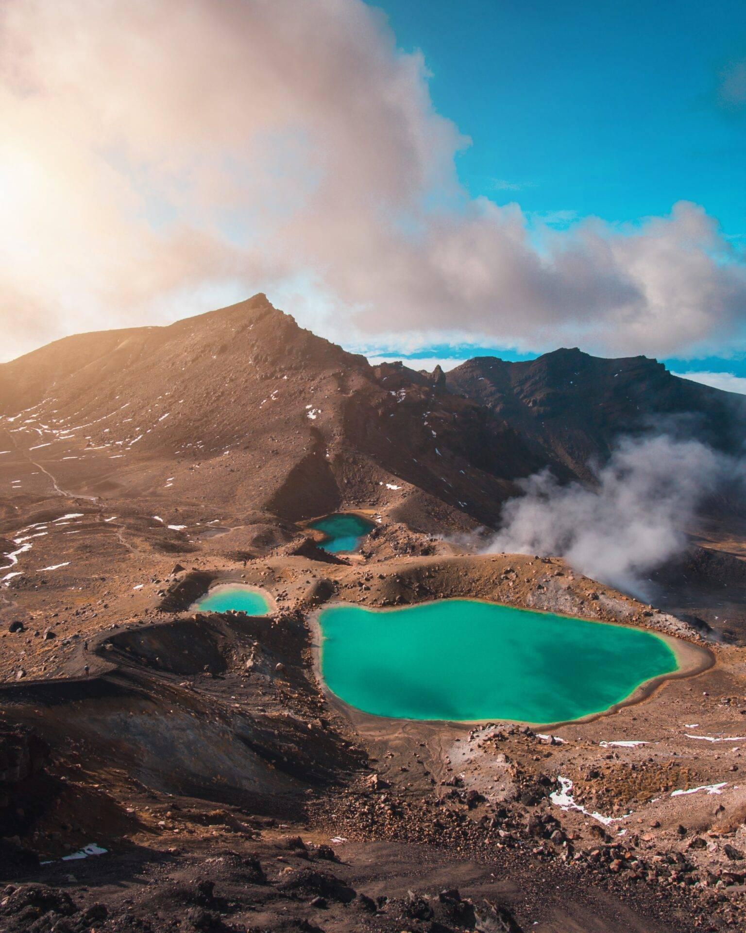 Vista aerea di laghi geotermici turchese immersi in un cratere vulcanico circondato da montagne