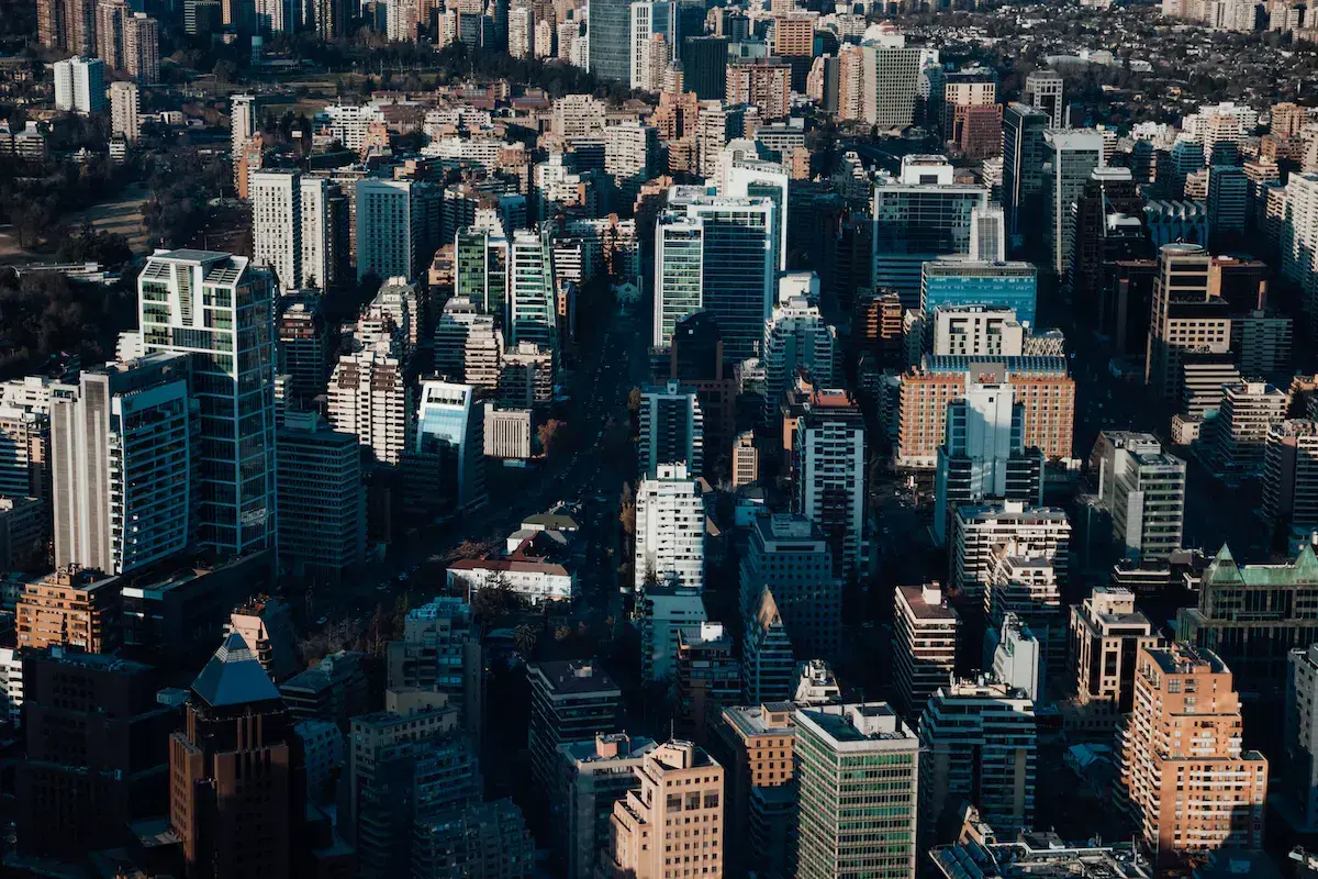 Vista aérea de una densa metrópoli con edificios de cristal, rascacielos y bloques residenciales bajo un cielo despejado
