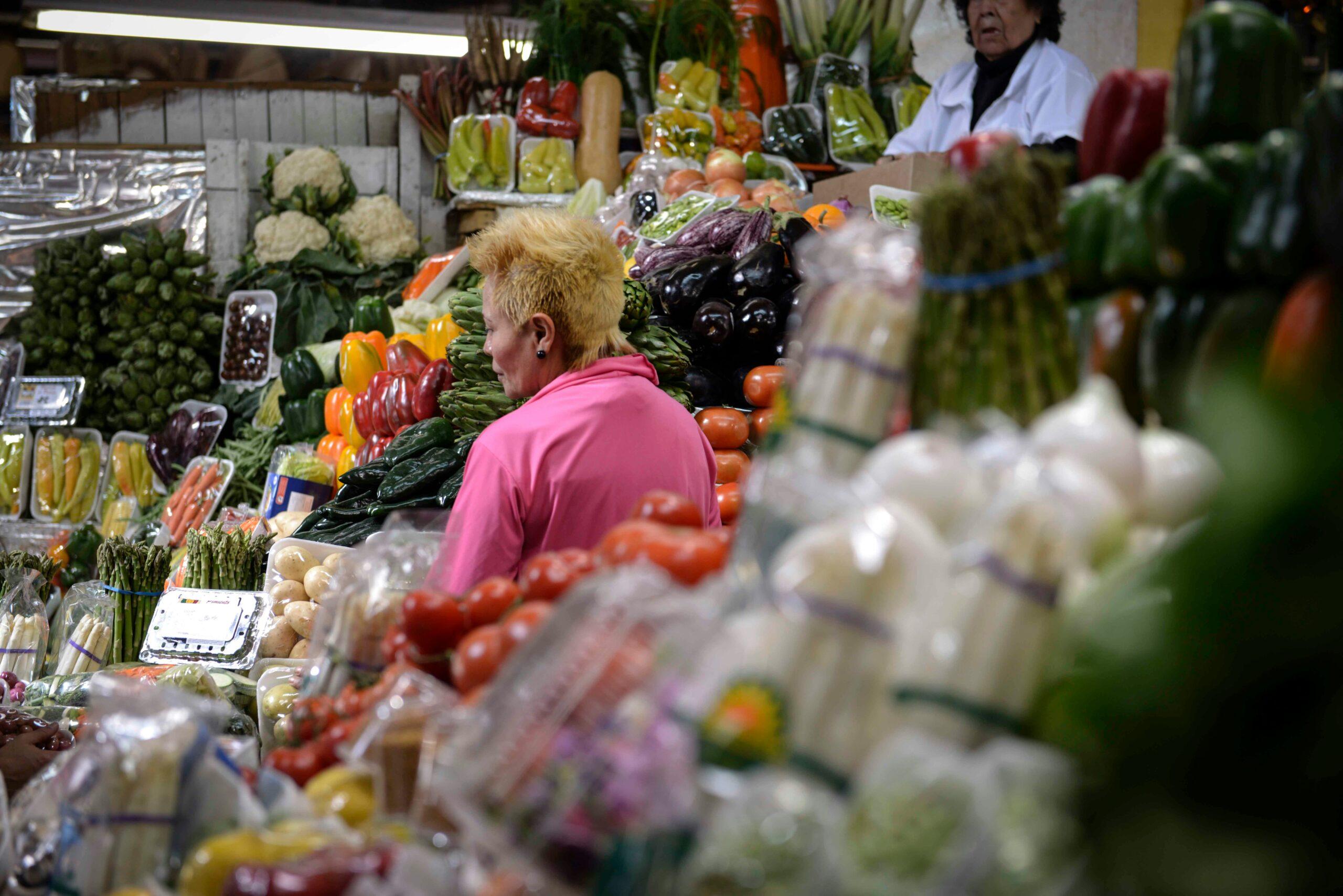 Une femme en rose fait ses courses au marché aux légumes frais colorés d’une ville andine
