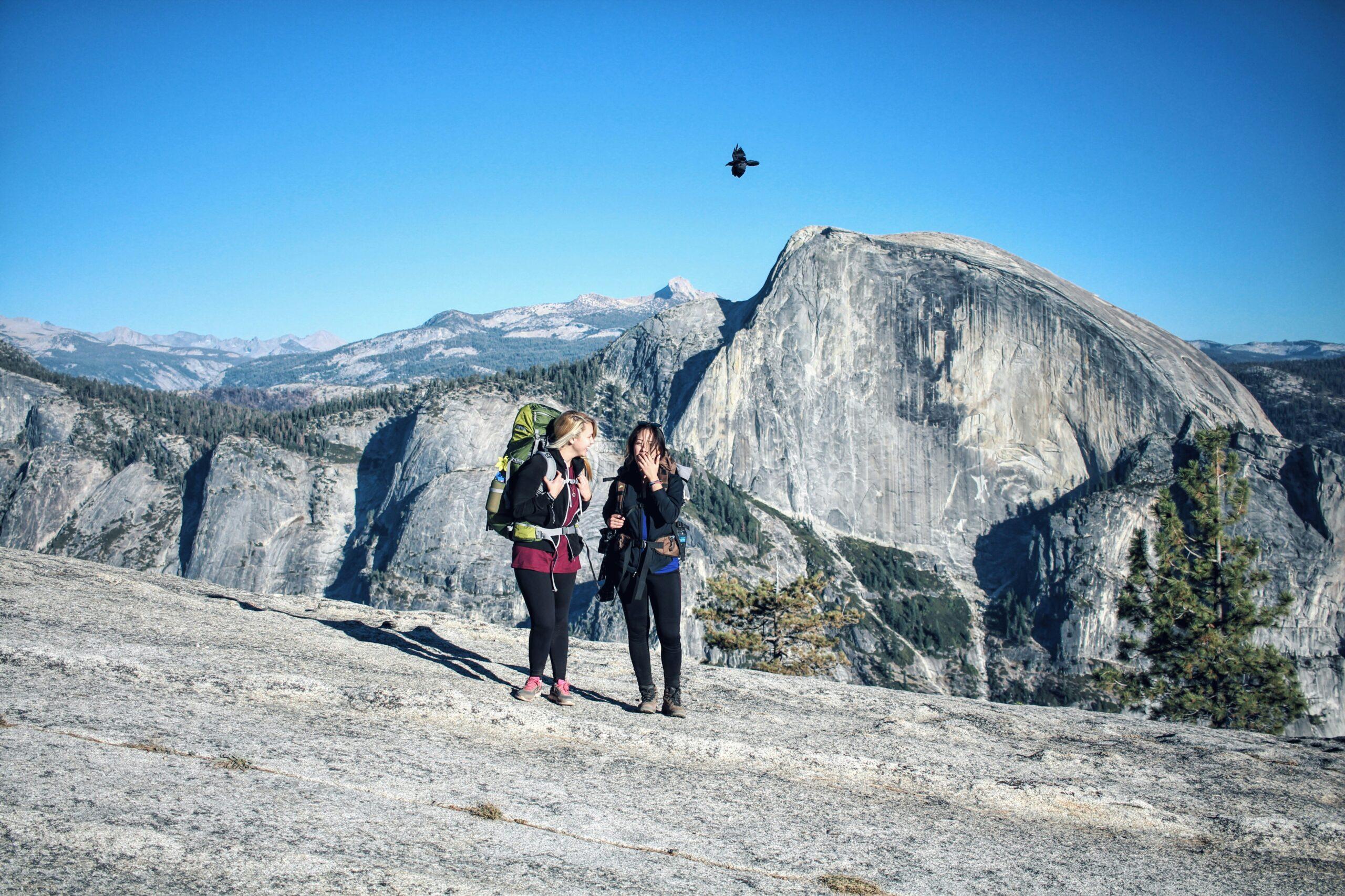 Senderista en un sendero alpino sobre el Valle de Yosemite con vistas a las paredes de granito