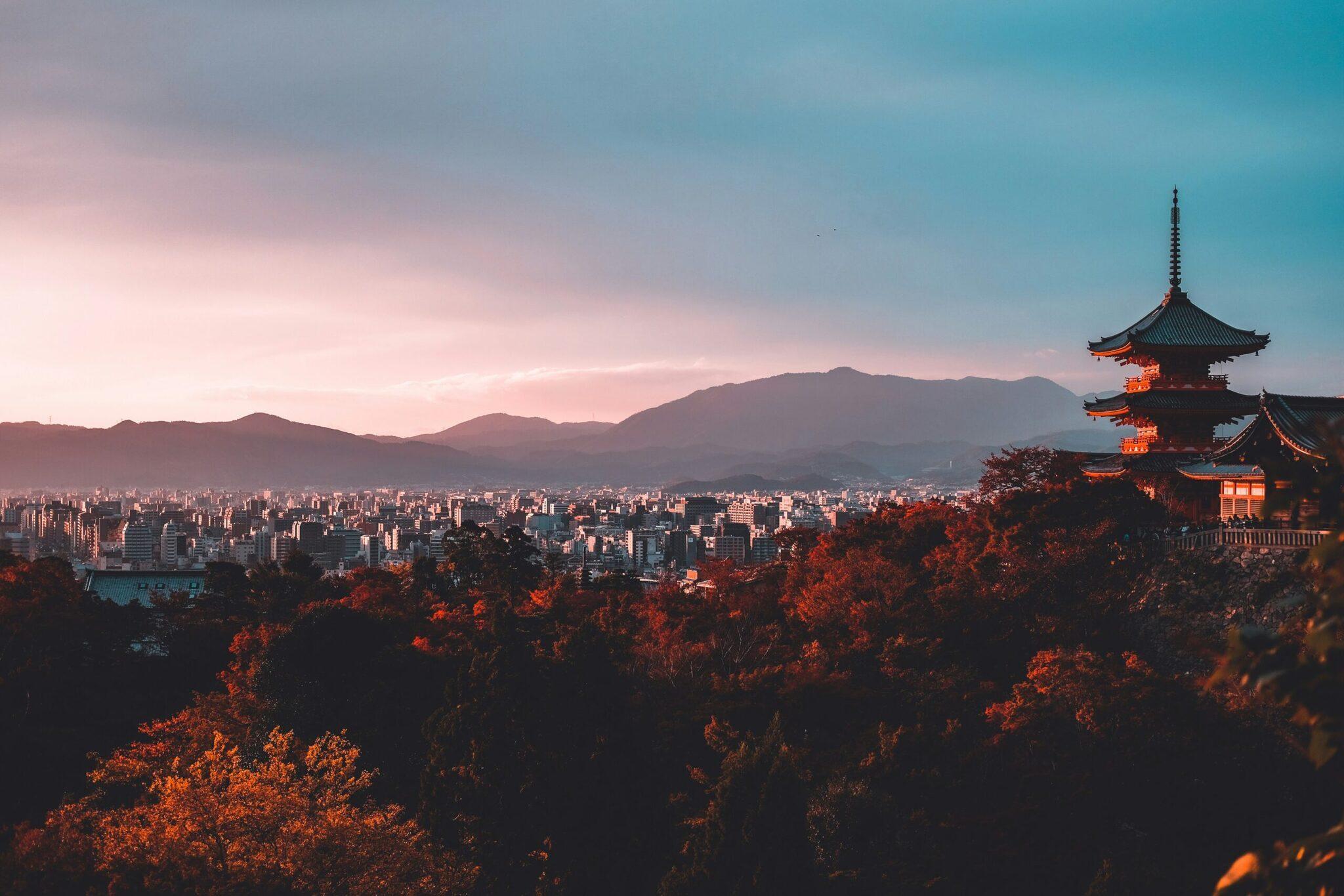 Un tempio asiatico dai tetti rossi domina una città di montagna al tramonto autunnale