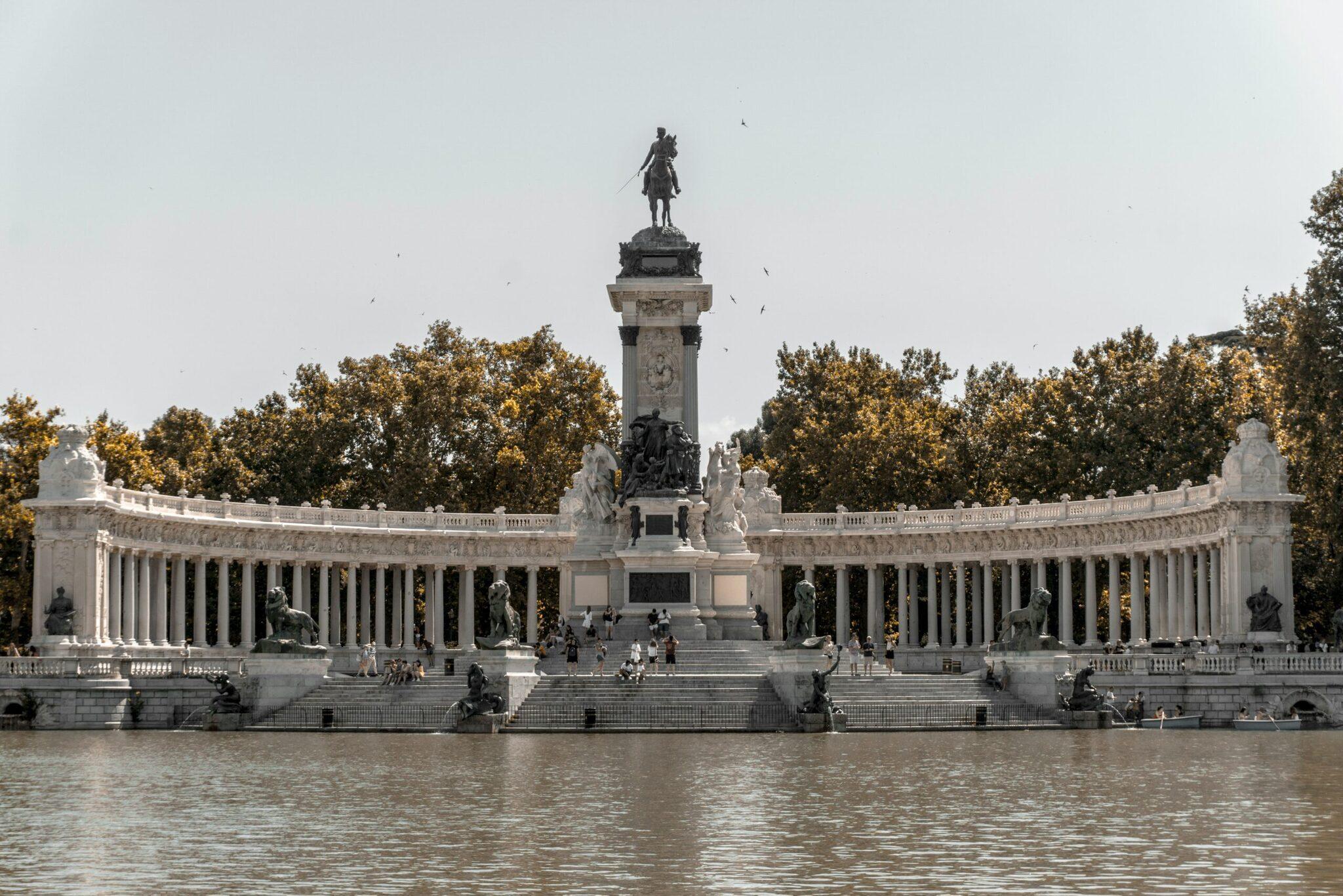 Monumento con colonnato bianco e statua equestre che si affaccia su uno specchio d’acqua, circondato da alberi