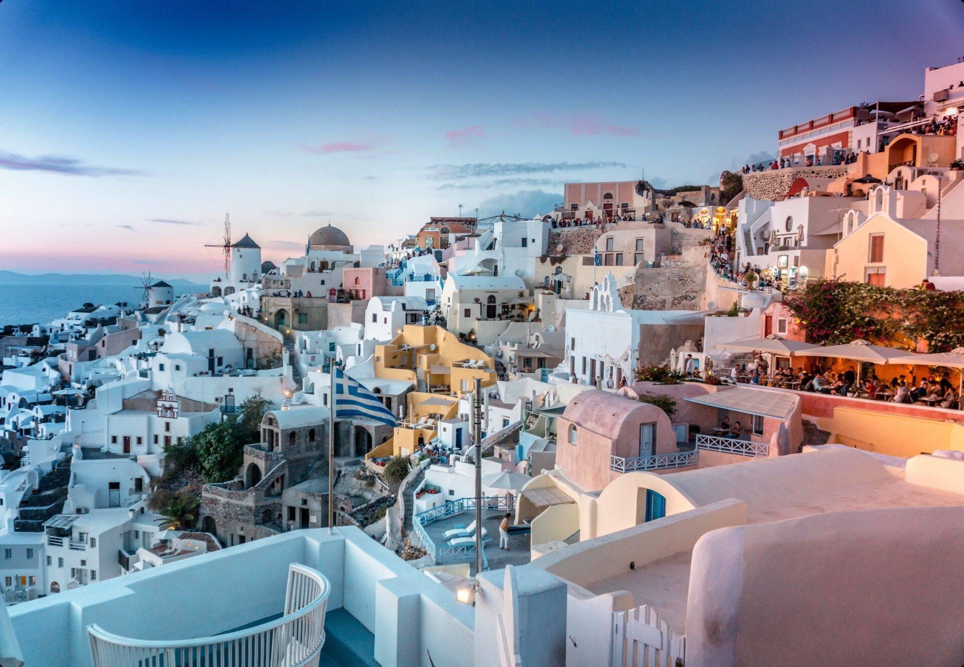 Panoramablick auf ein buntes weißes Dorf, das beim Sonnenuntergang auf einer mediterranen Klippe thront