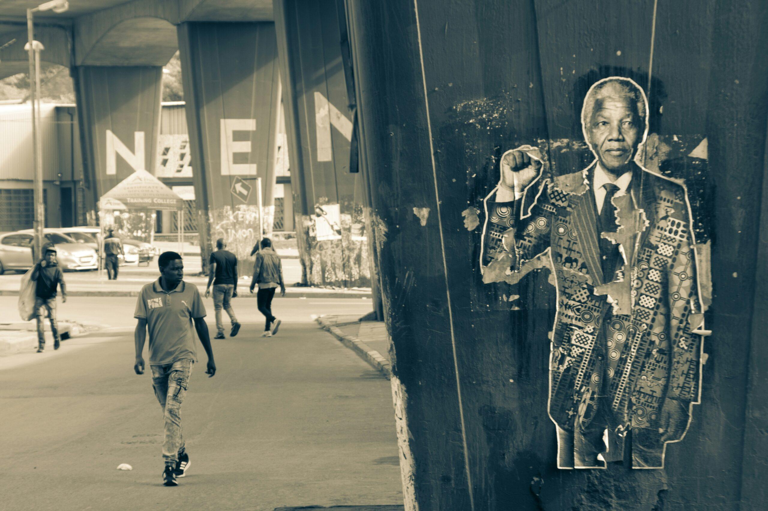 Retrato de street art en una pared urbana con transeúntes en una calle de Johannesburgo
