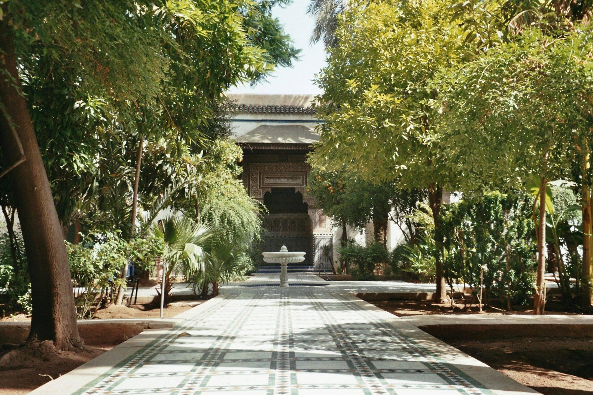 Paseo sombreado de un palacio marroquí con fuente central y arquitectura tradicional ornamentada