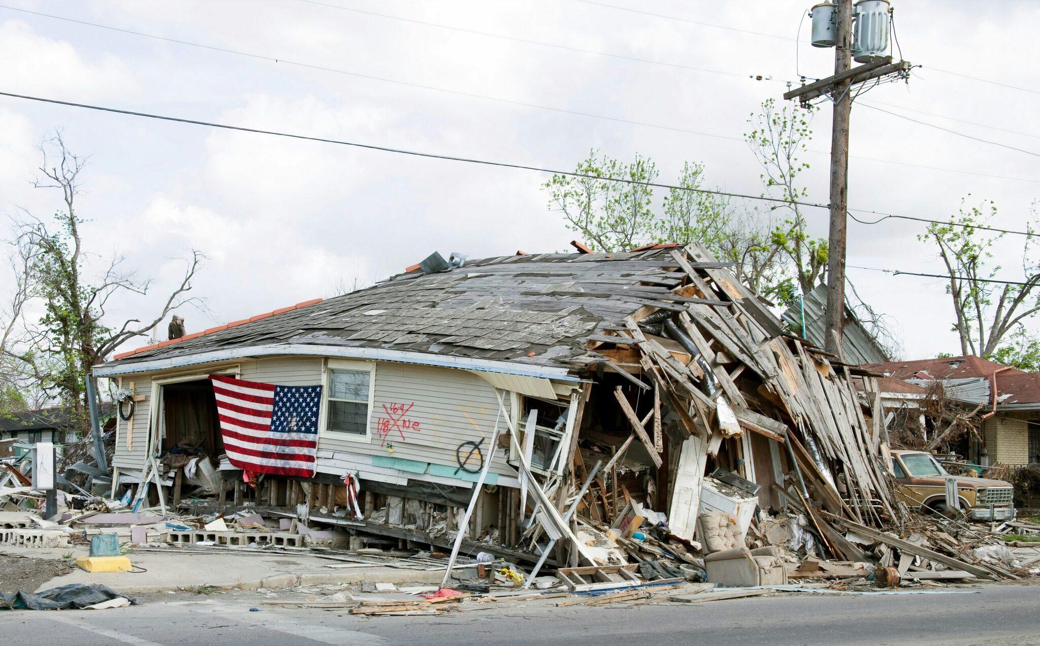 Casa gravemente danneggiata da una catastrofe naturale con bandiera americana, a testimonianza dei danni subiti da New Orleans