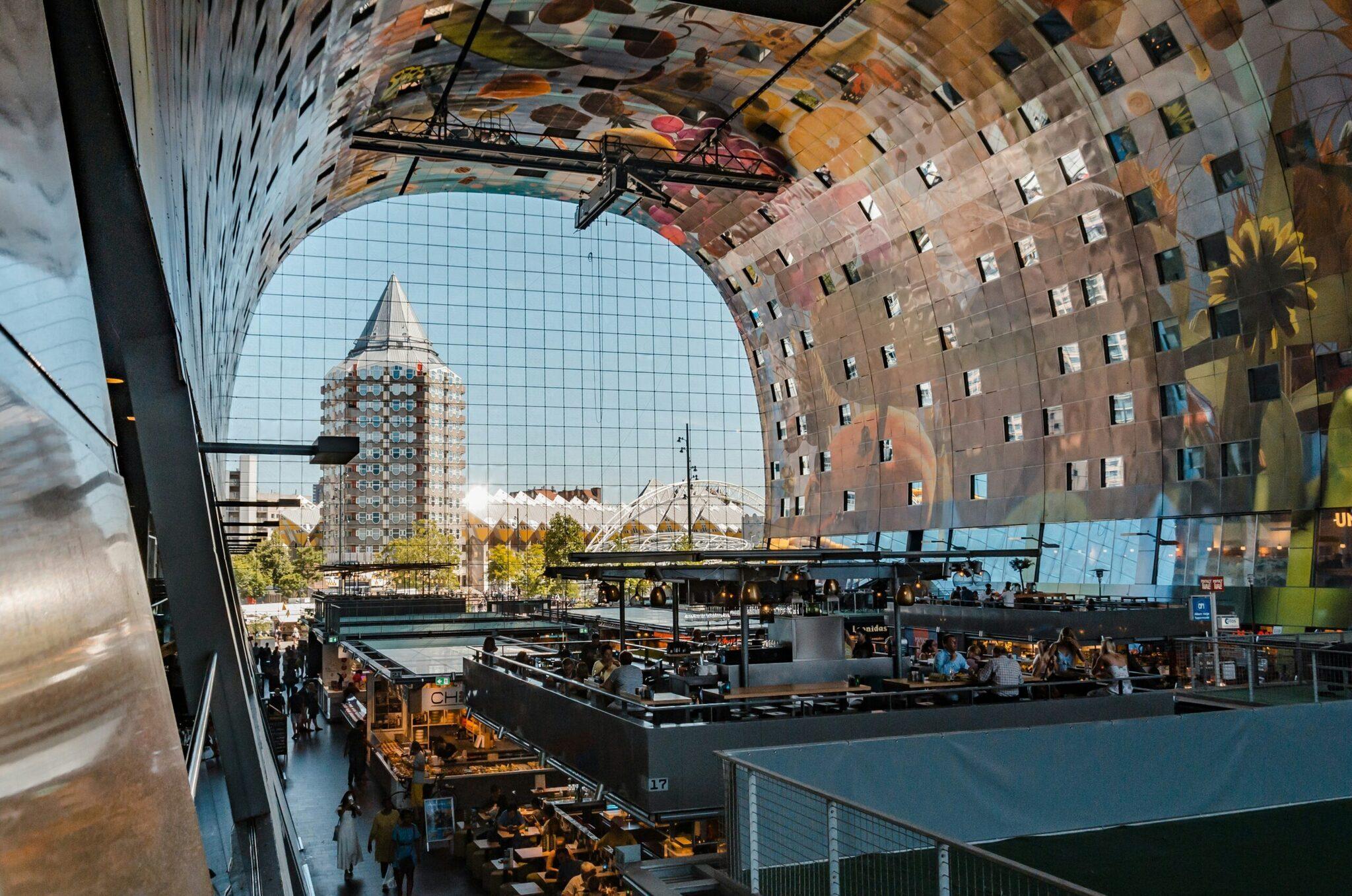 Blick aus einem modernen Gebäude auf einen belebten öffentlichen Platz mit zeitgenössischer Architektur und Wohnhäusern