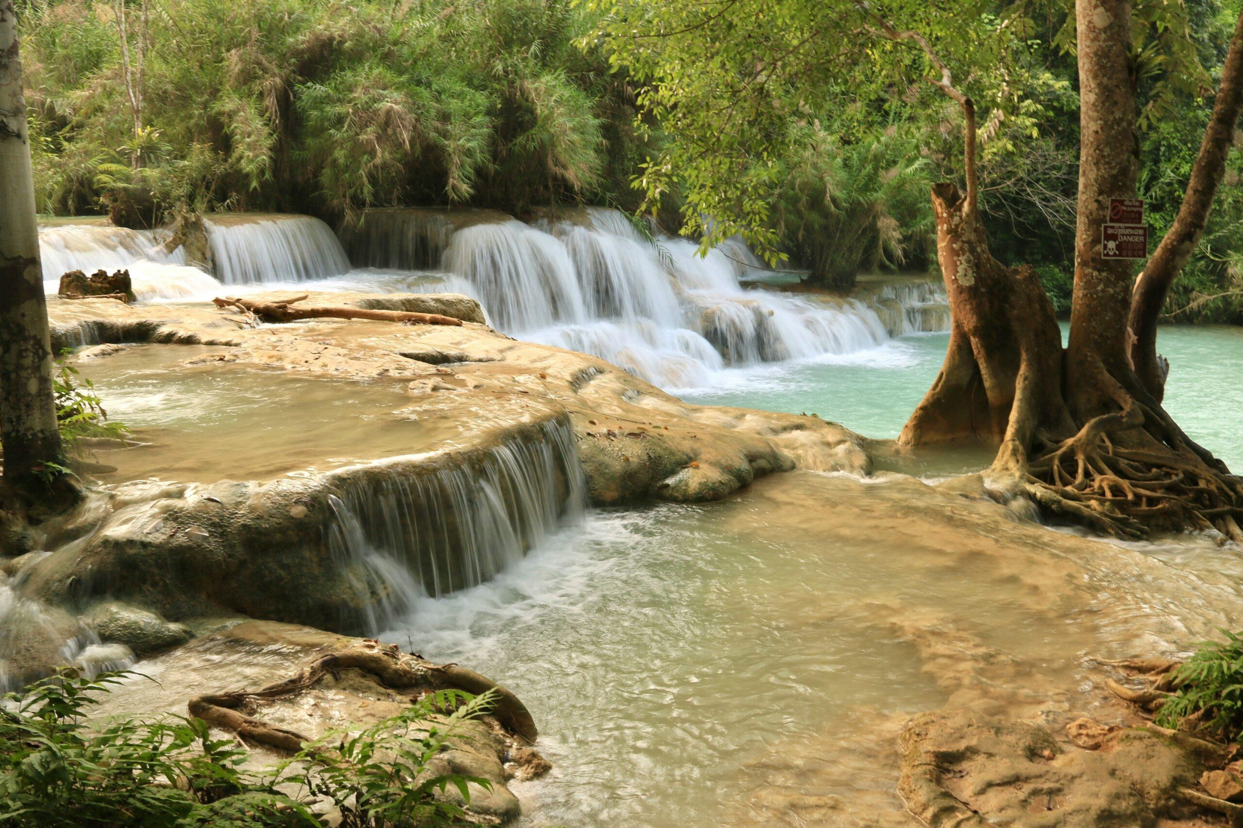 Mehrstufige Wasserfälle in einem üppigen tropischen Regenwald mit türkisfarbenen Becken und Bäumen mit freigelegten Wurzeln