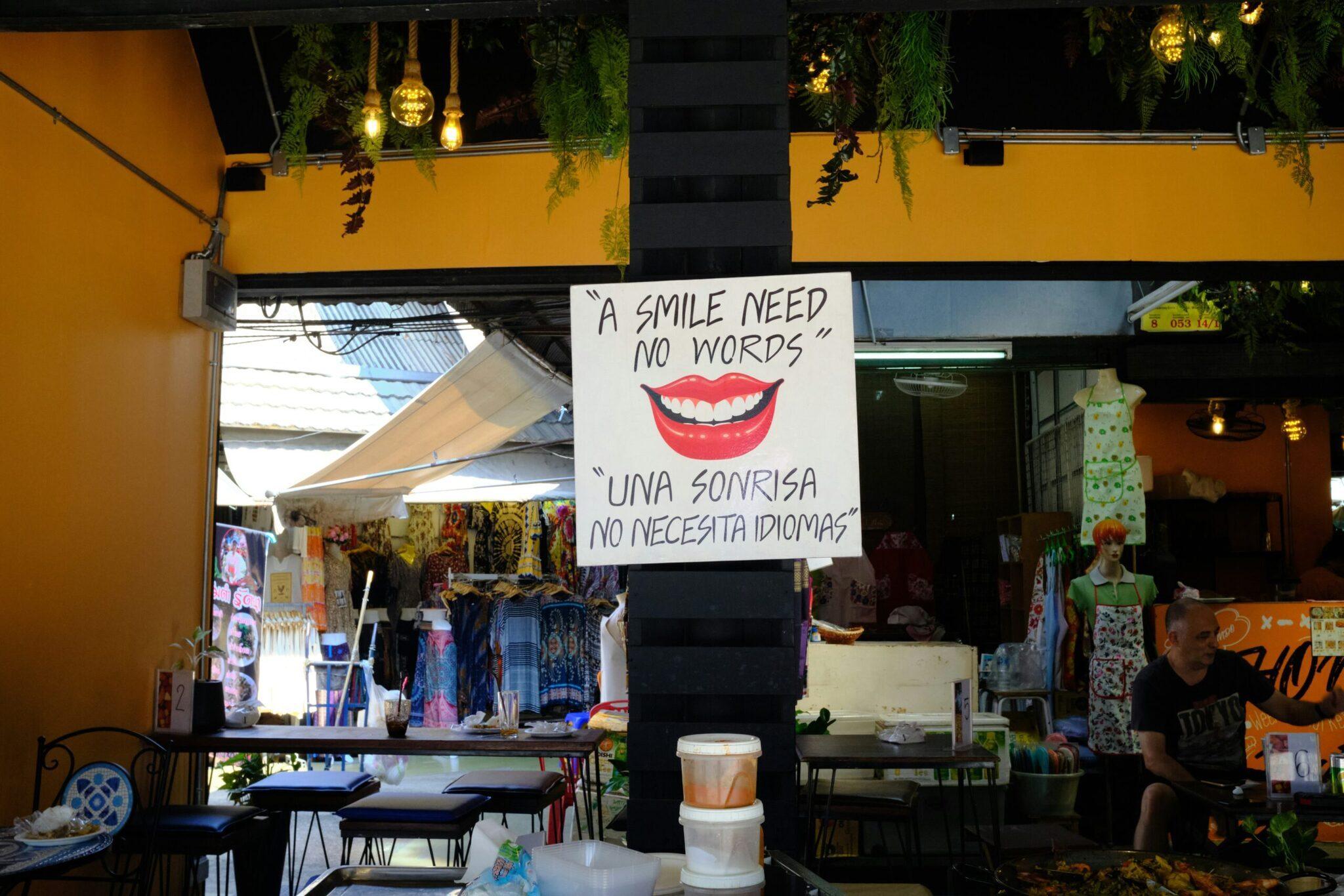 Colourful shopfront on a market street with a bilingual English-Spanish sign and bright yellow decoration