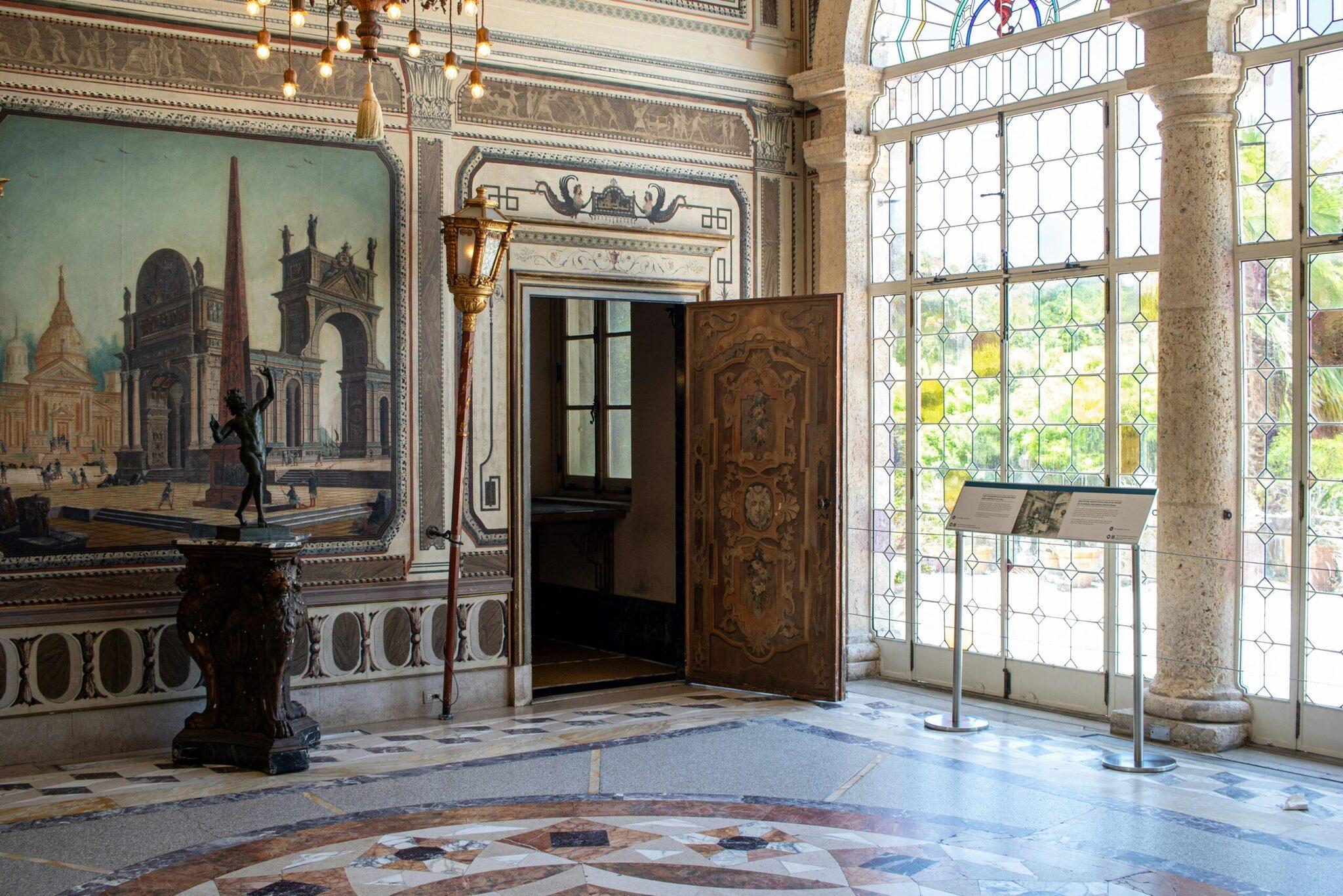 Elegant palace interior with painted wall murals, marble columns and tall geometric stained-glass windows