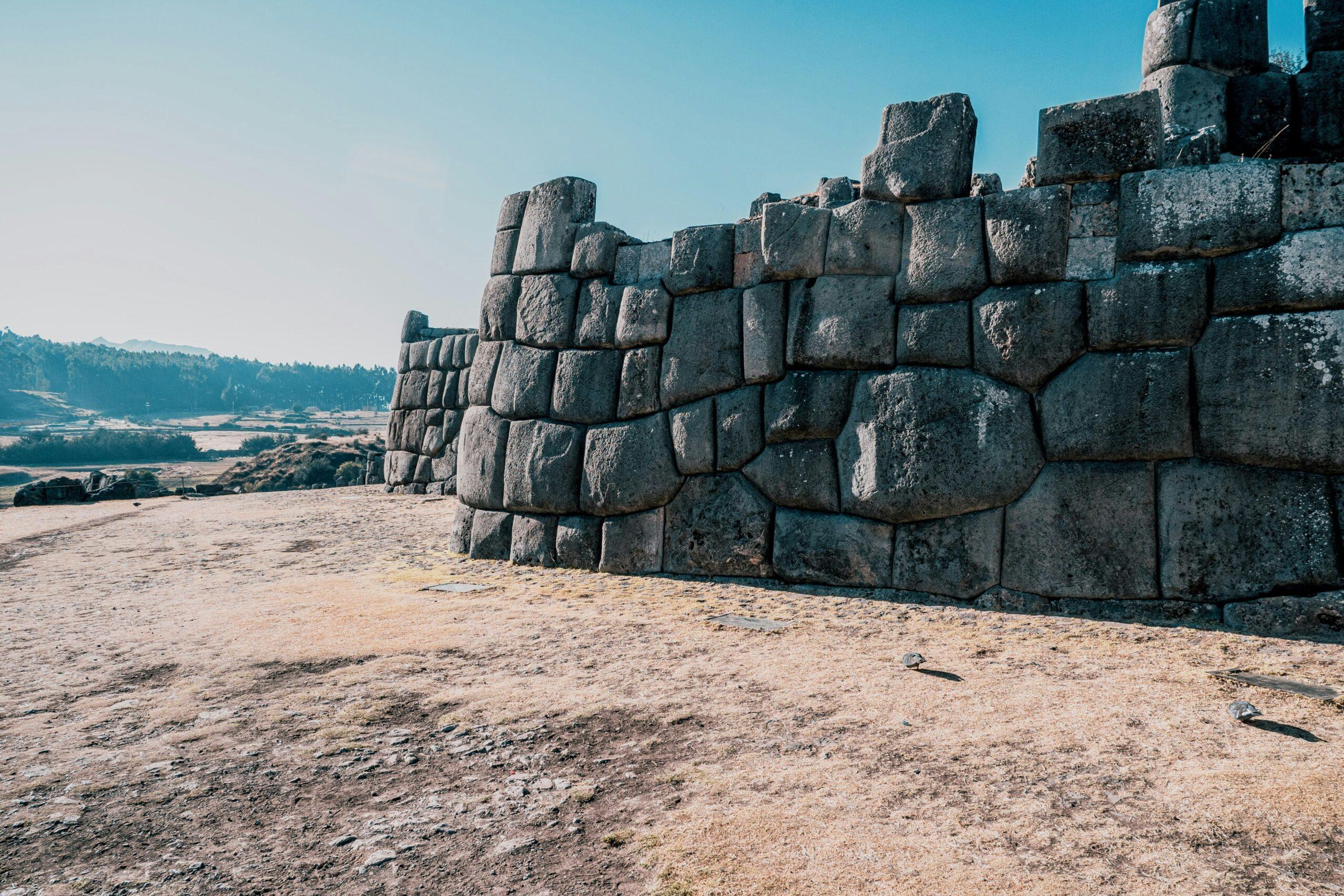 Imposants murs de pierres incas parfaitement empilées dominant une vallée verdoyante sous un ciel dégagé
