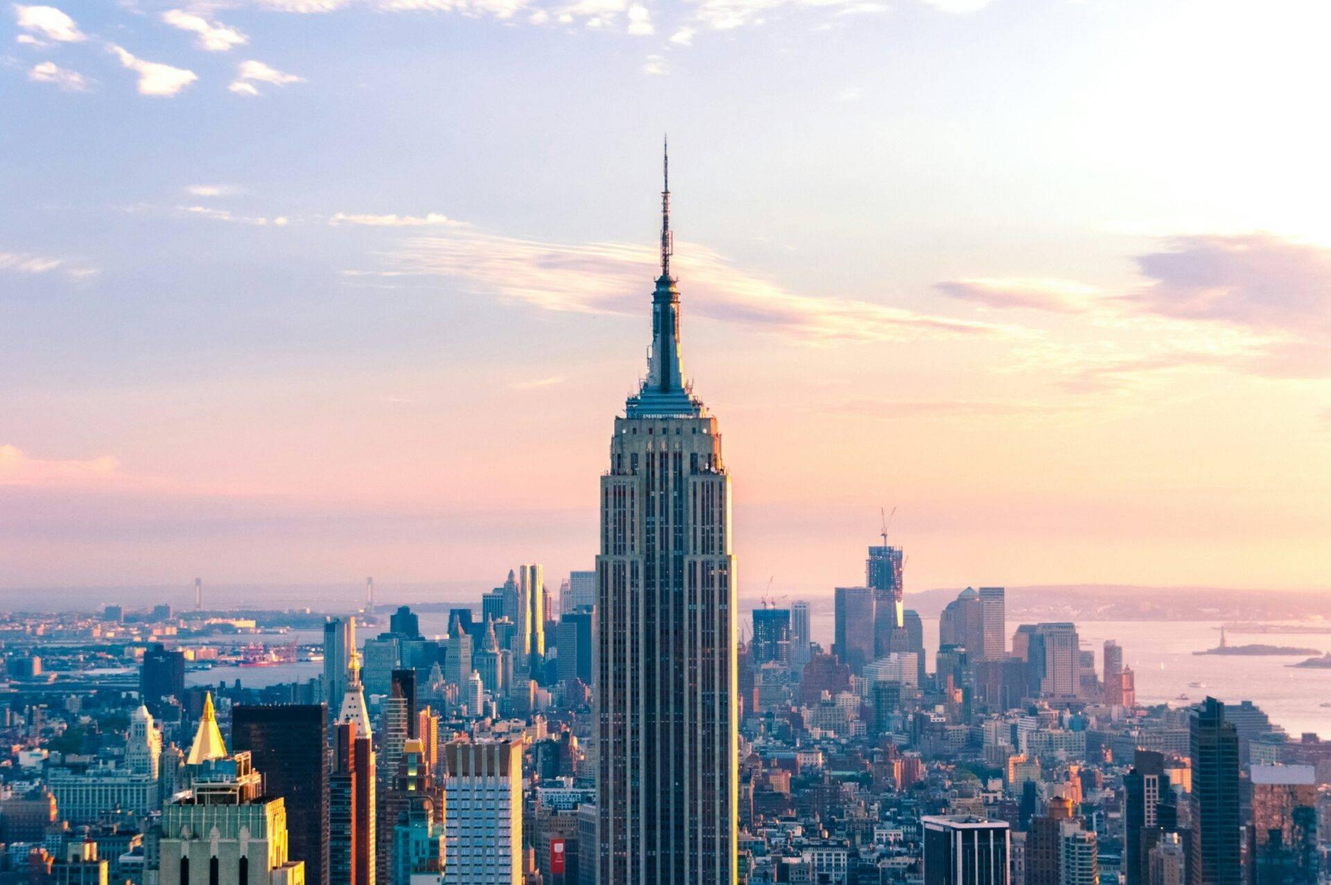 Vue panoramique sur un gratte-ciel emblématique dominant une dense skyline urbaine avec rivière en arrière-plan au coucher de soleil