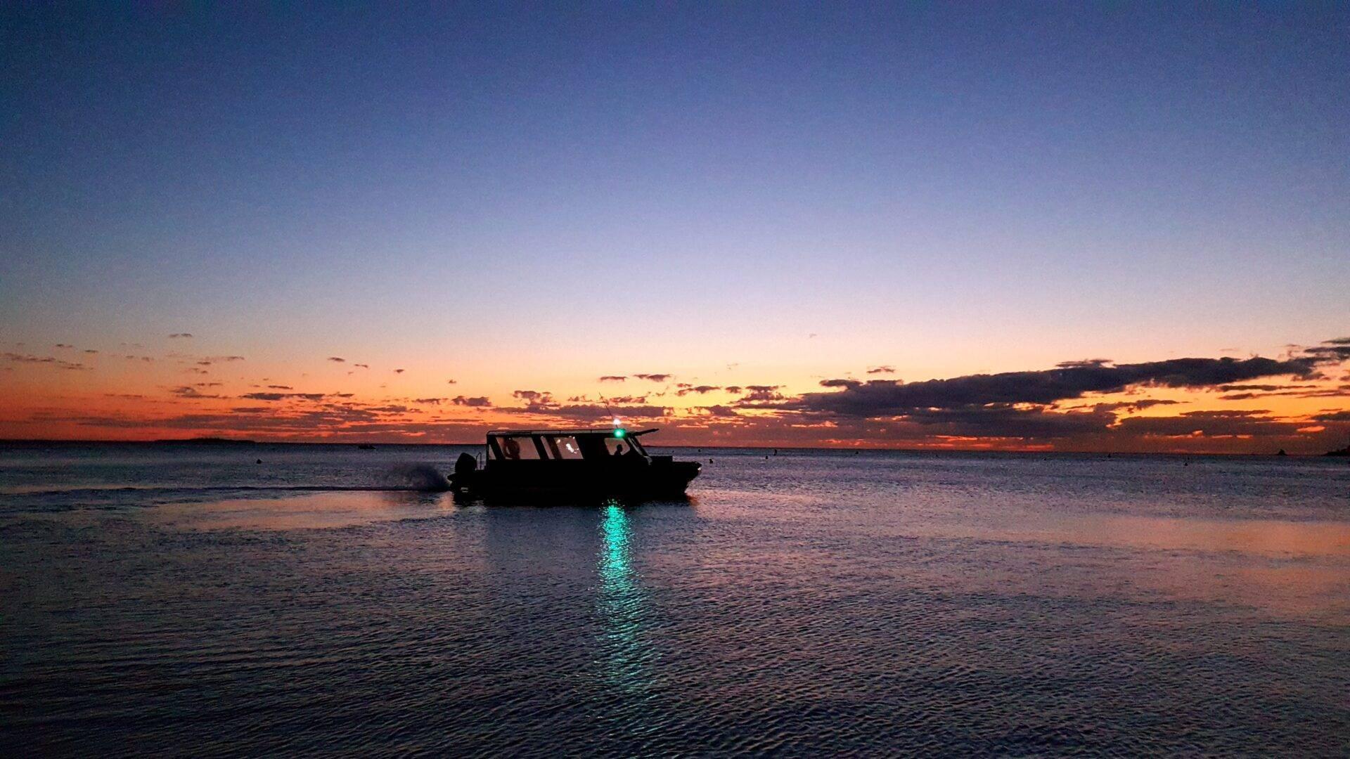 Ein Motorboot als Silhouette beim Sonnenuntergang auf einem ruhigen, stillen Meer