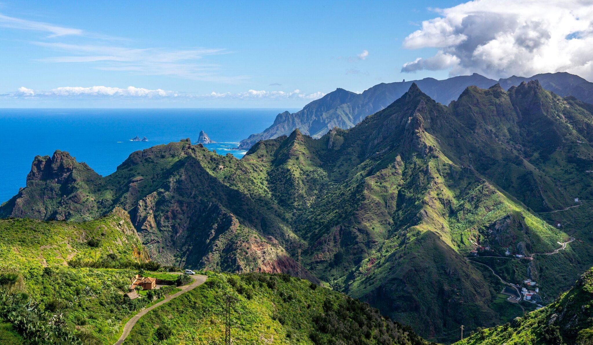 Vista aérea de montañas verdes y escarpadas que dominan un mar turquesa bajo un cielo despejado