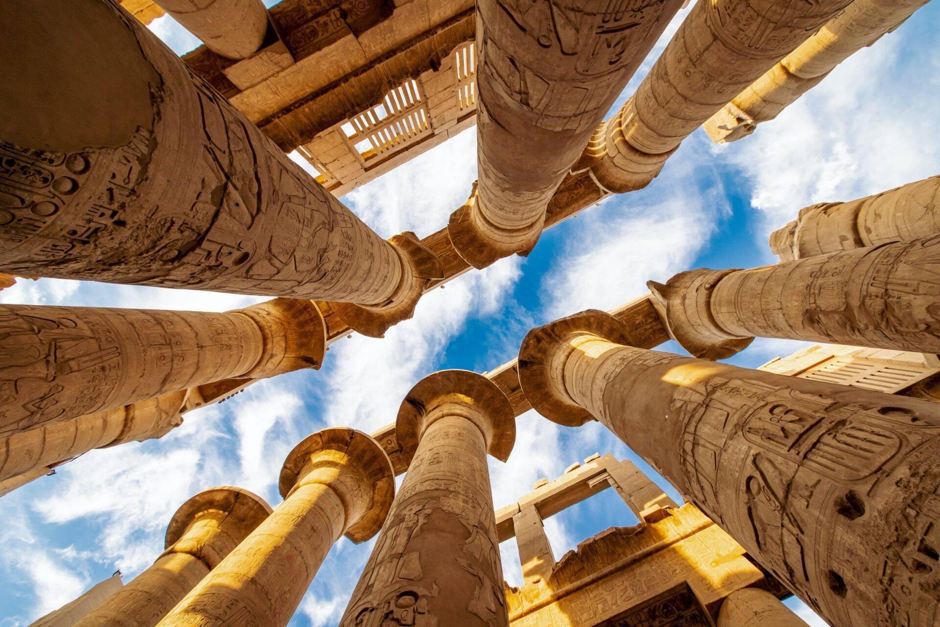 Vista dal basso di colonne faraoniche ornate di geroglifici in un antico tempio egizio