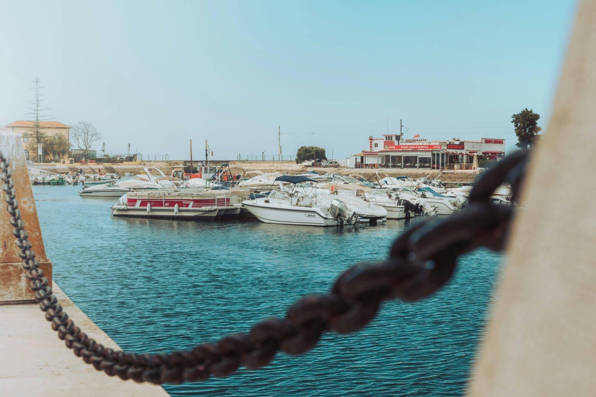Ein kleiner mediterraner Hafen mit Fischerbooten und einem Strandrestaurant unter klarem Himmel