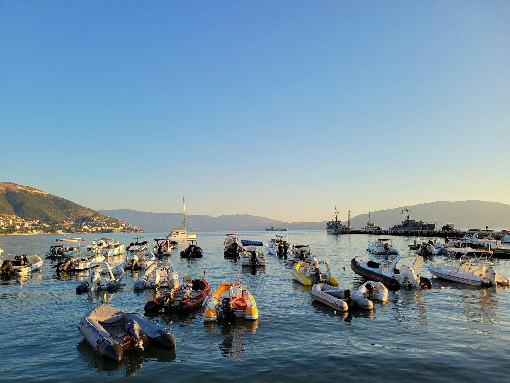 Ein mediterraner Hafen mit bunten Booten in einer kristallklaren Bucht, umgeben von Bergen