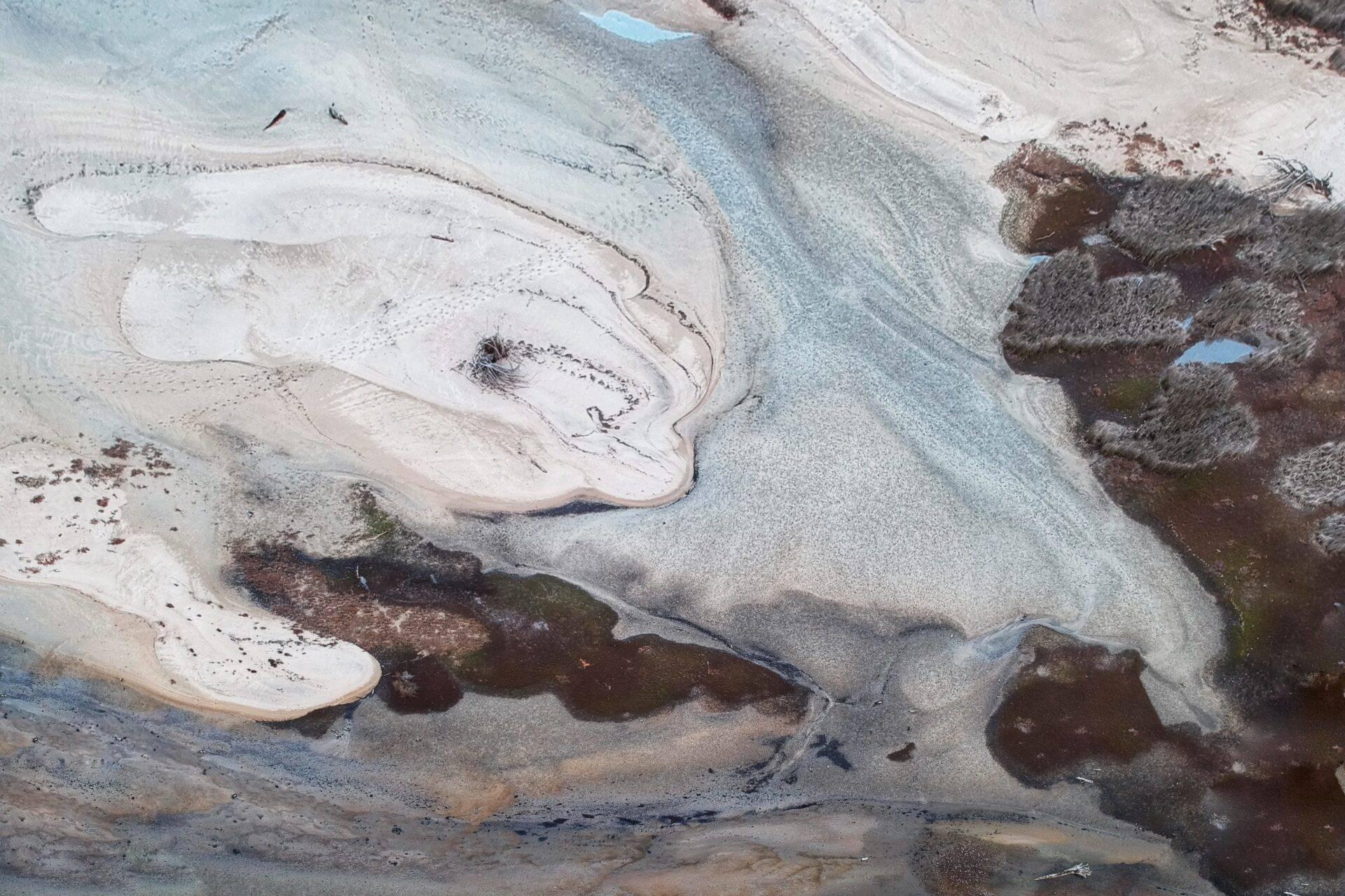 Vista aerea di bacini geotermici dalle acque turchese circondati da formazioni minerali colorate in bianco e marrone
